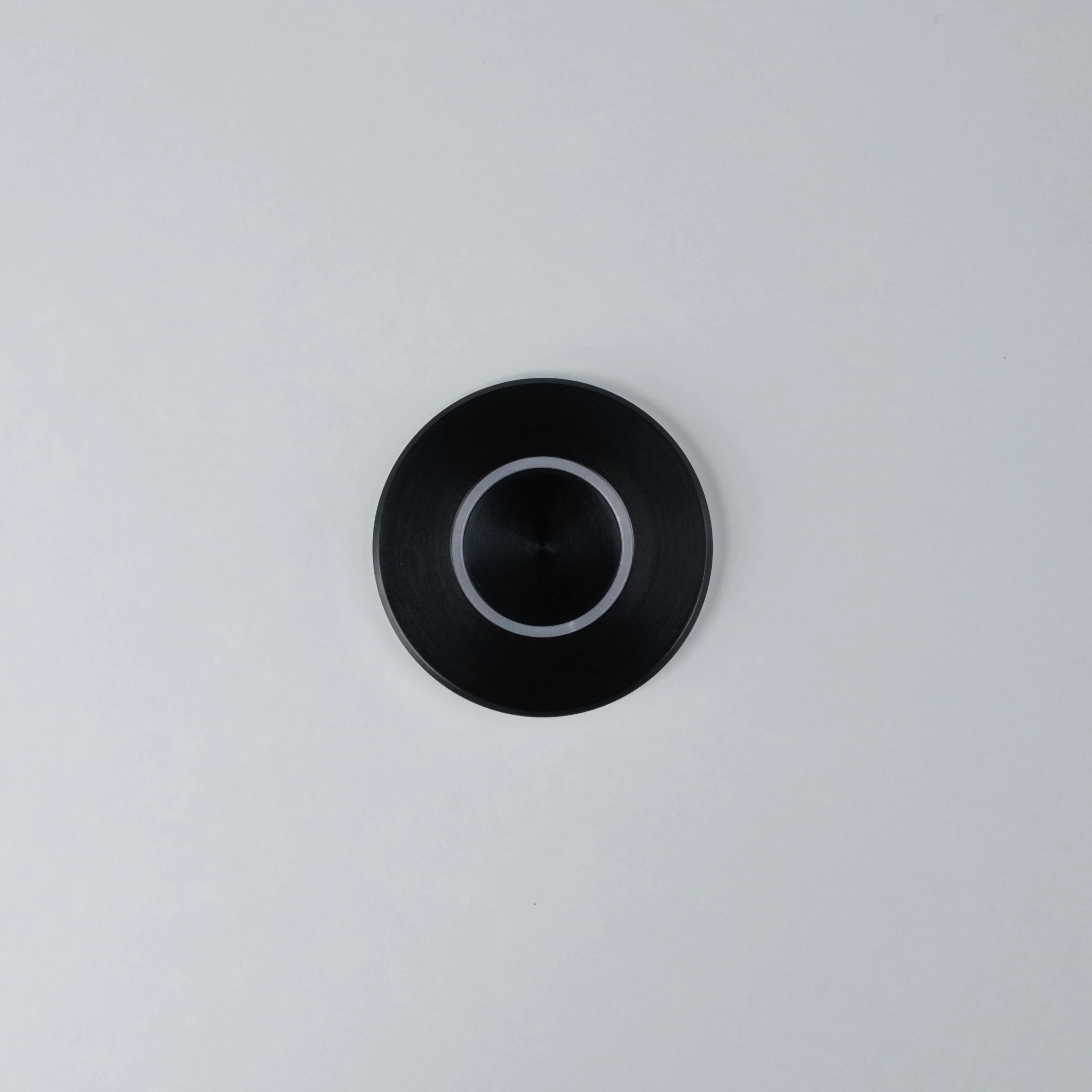 Black Nuki Button, round, integrated in a white door – turns a mechanical lock into a smart door.