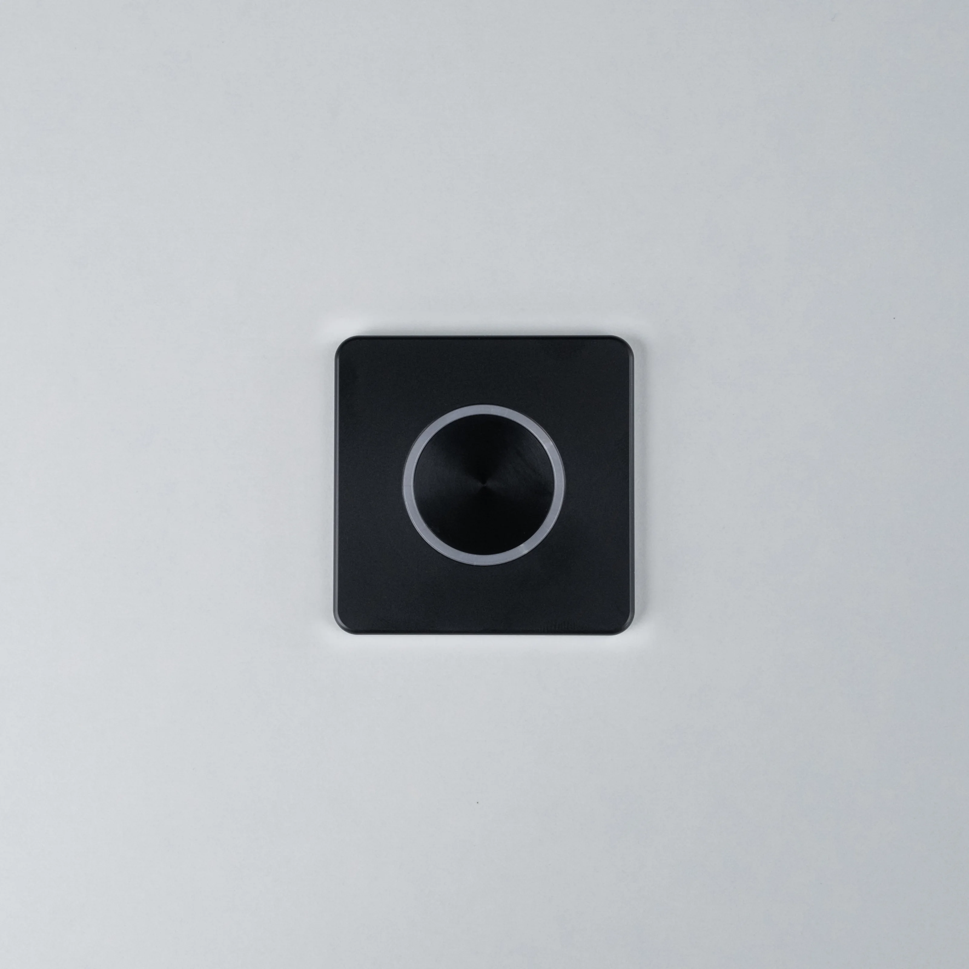 Black Nuki Button, square, integrated in a white door – turns a mechanical lock into a smart door.