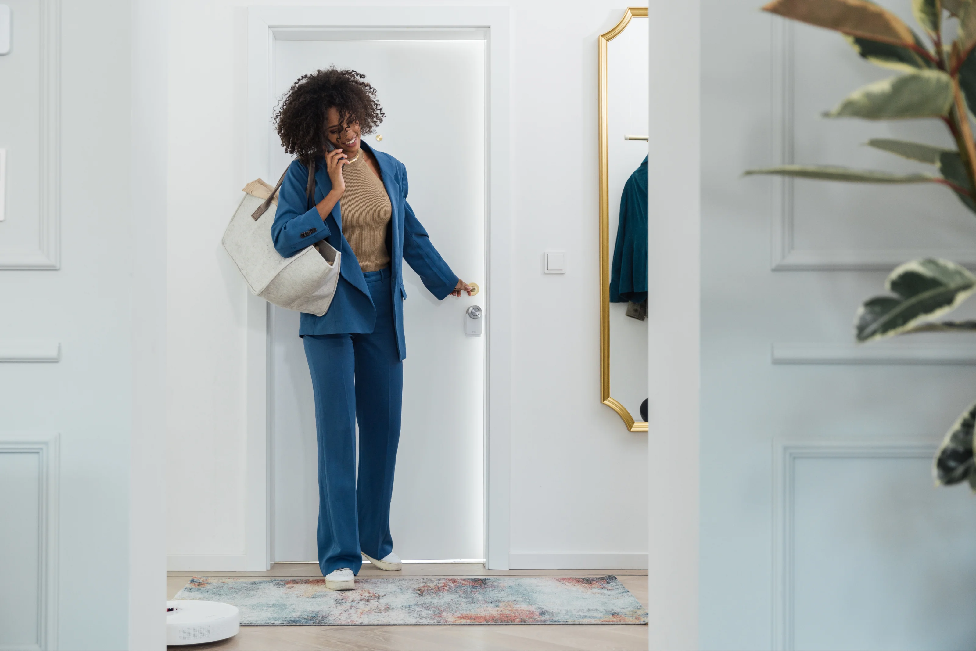 Woman unlocking door with smartphone using a Nuki Smart Lock while entering modern home.