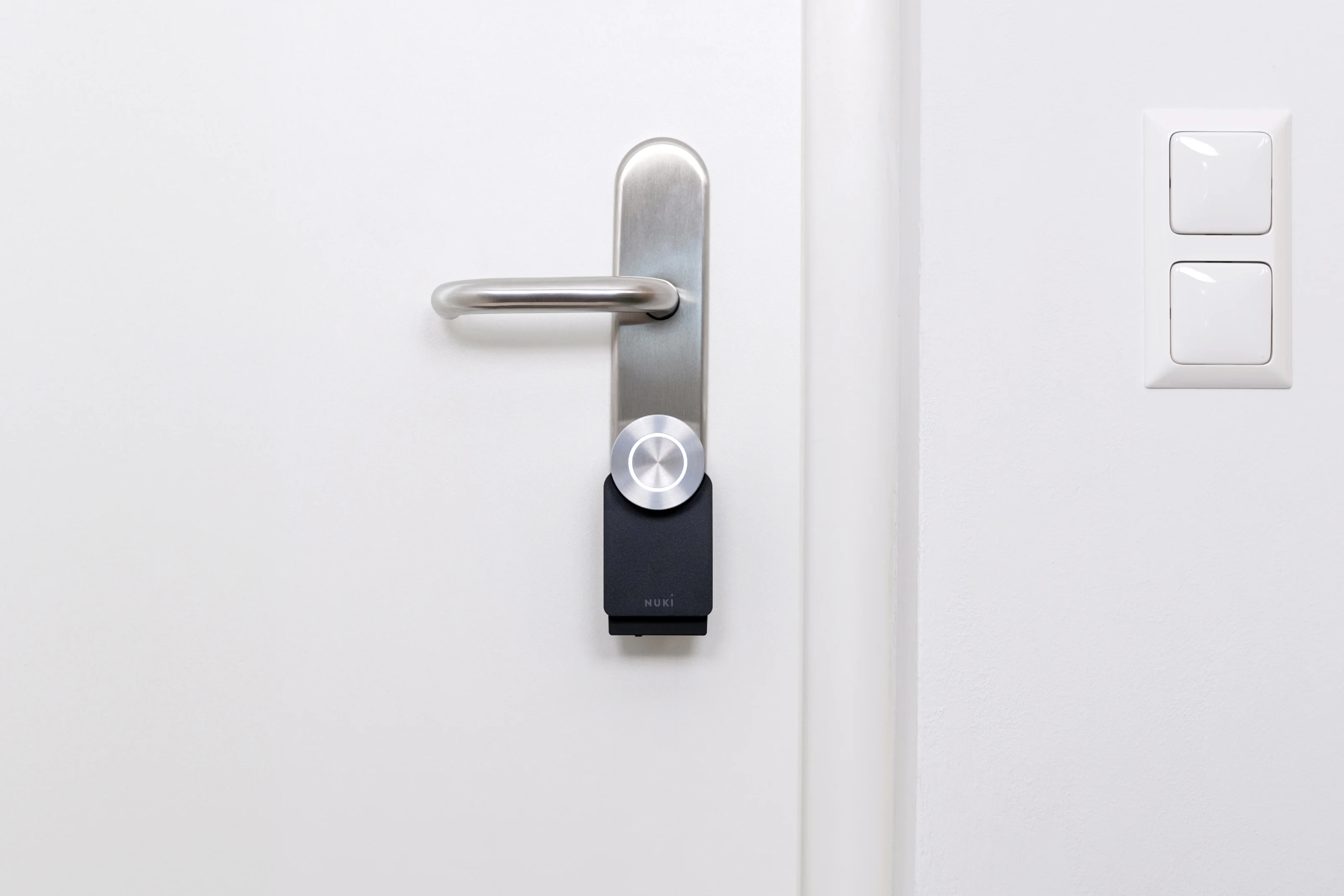 Nuki Smart Lock installed on a white door with stainless steel handle, ready for keyless smart access.