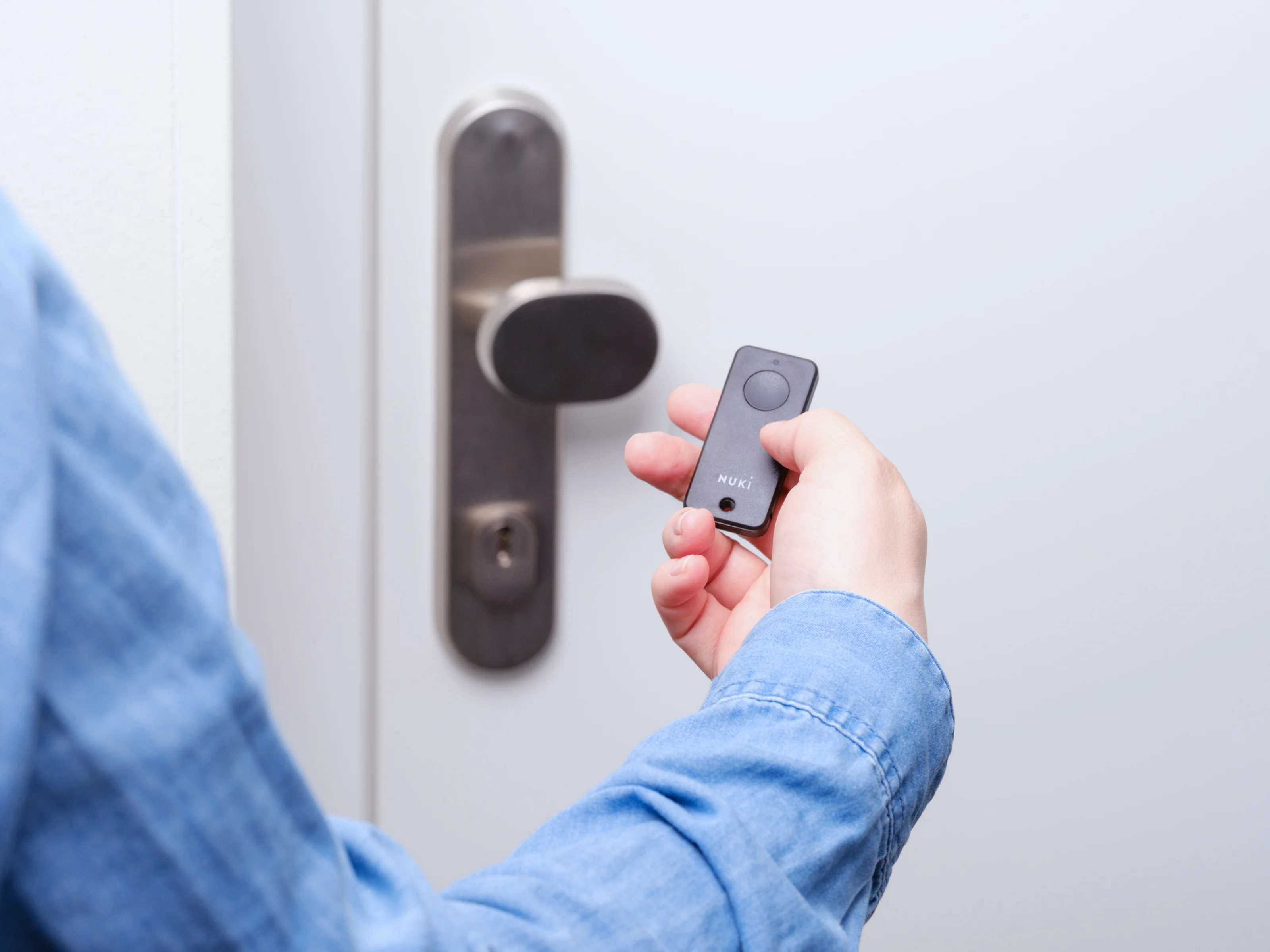 Person unlocking a door with the Nuki Fob and Nuki Smart Lock.