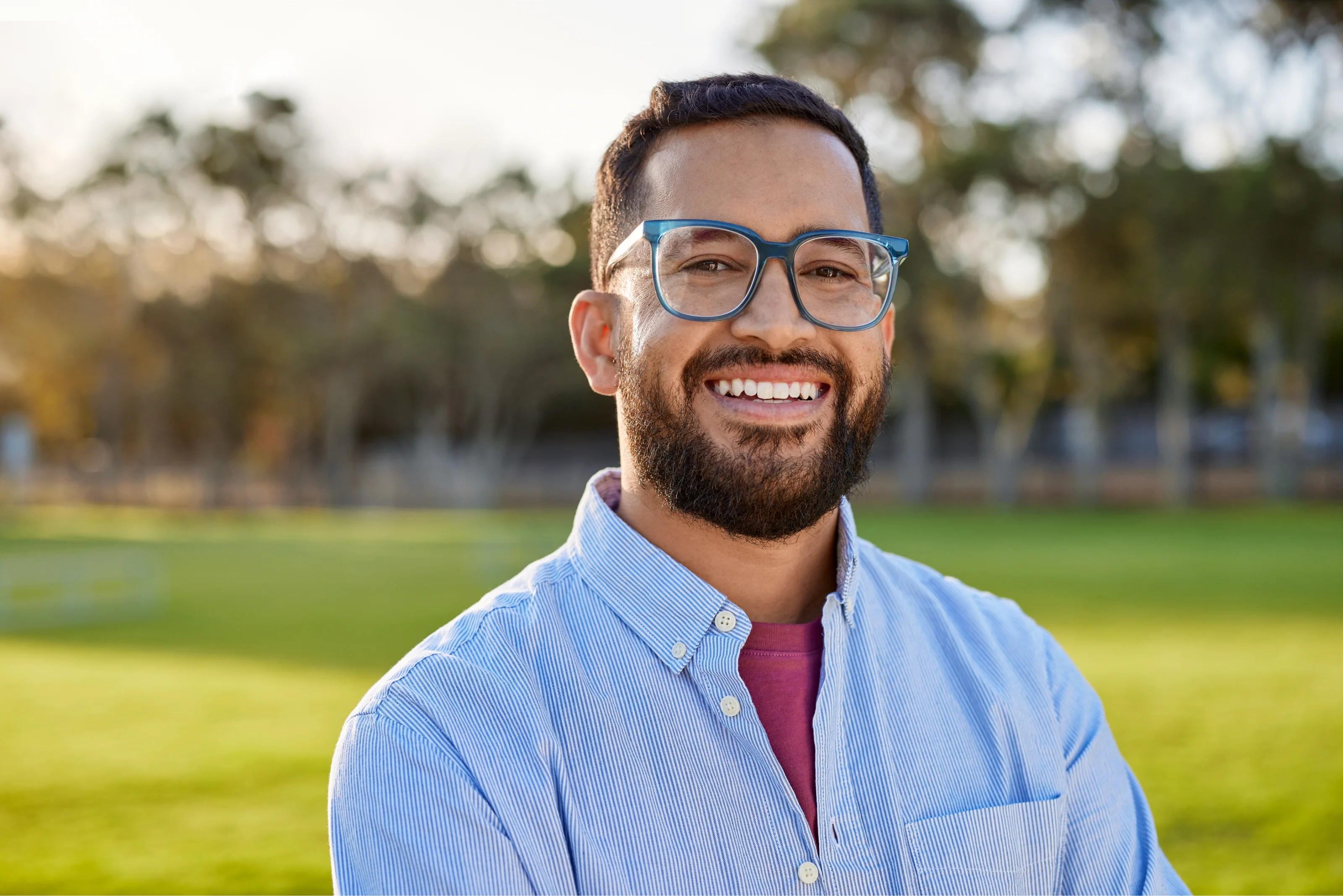 A man standing in a park with a big smile on his face