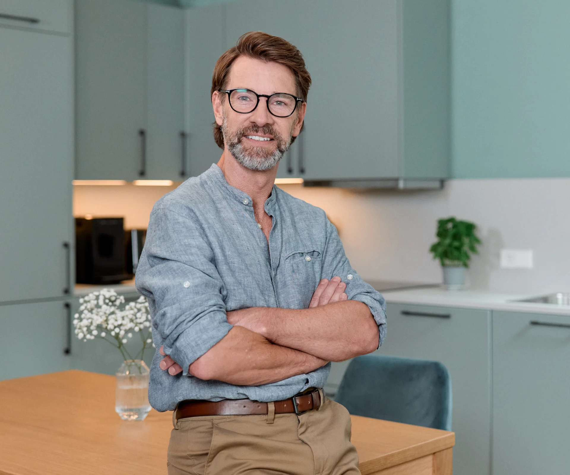 Man standing in apartment with folded arms.