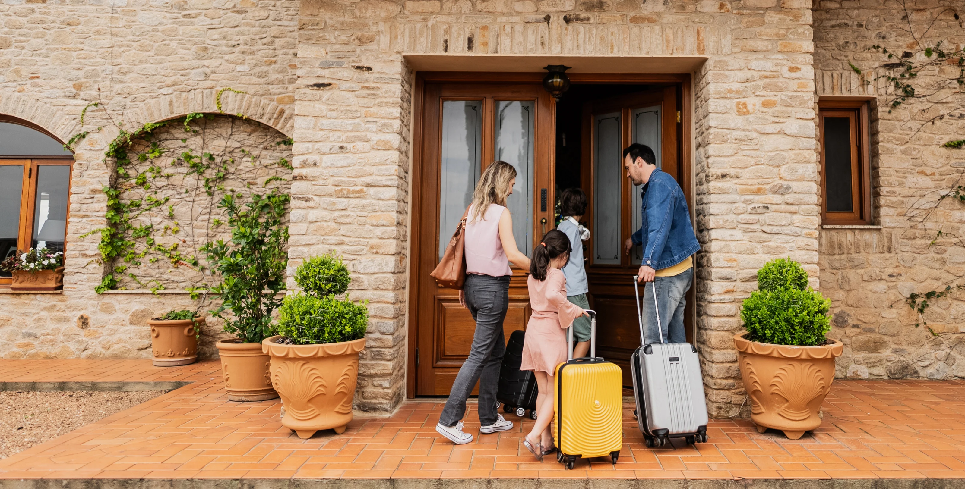 A family with suitcases arriving and unlocking the door of a holiday home using a Nuki Keypad.