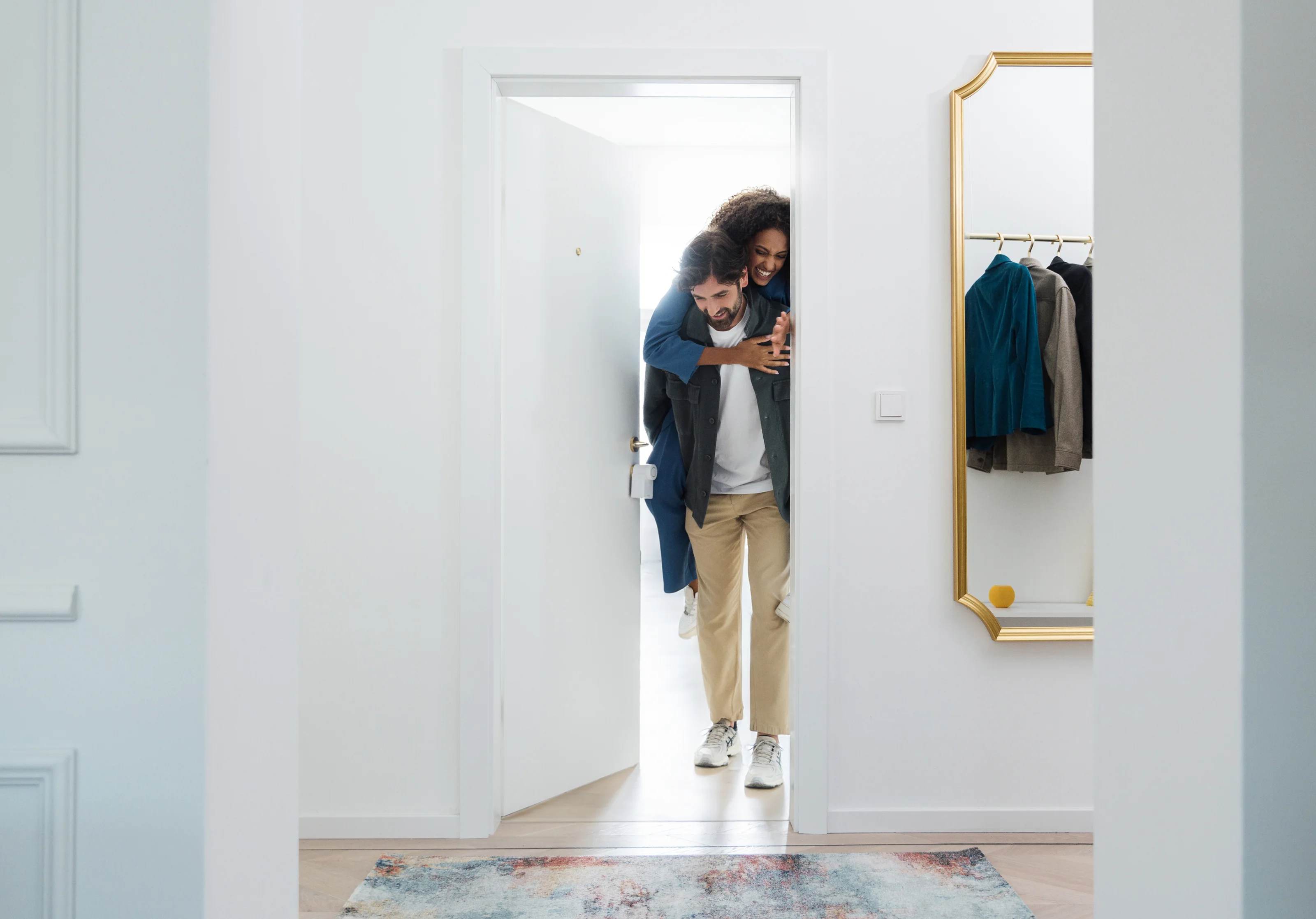 Couple enters home joyfully through a door equipped with the Nuki Smart Lock Go.