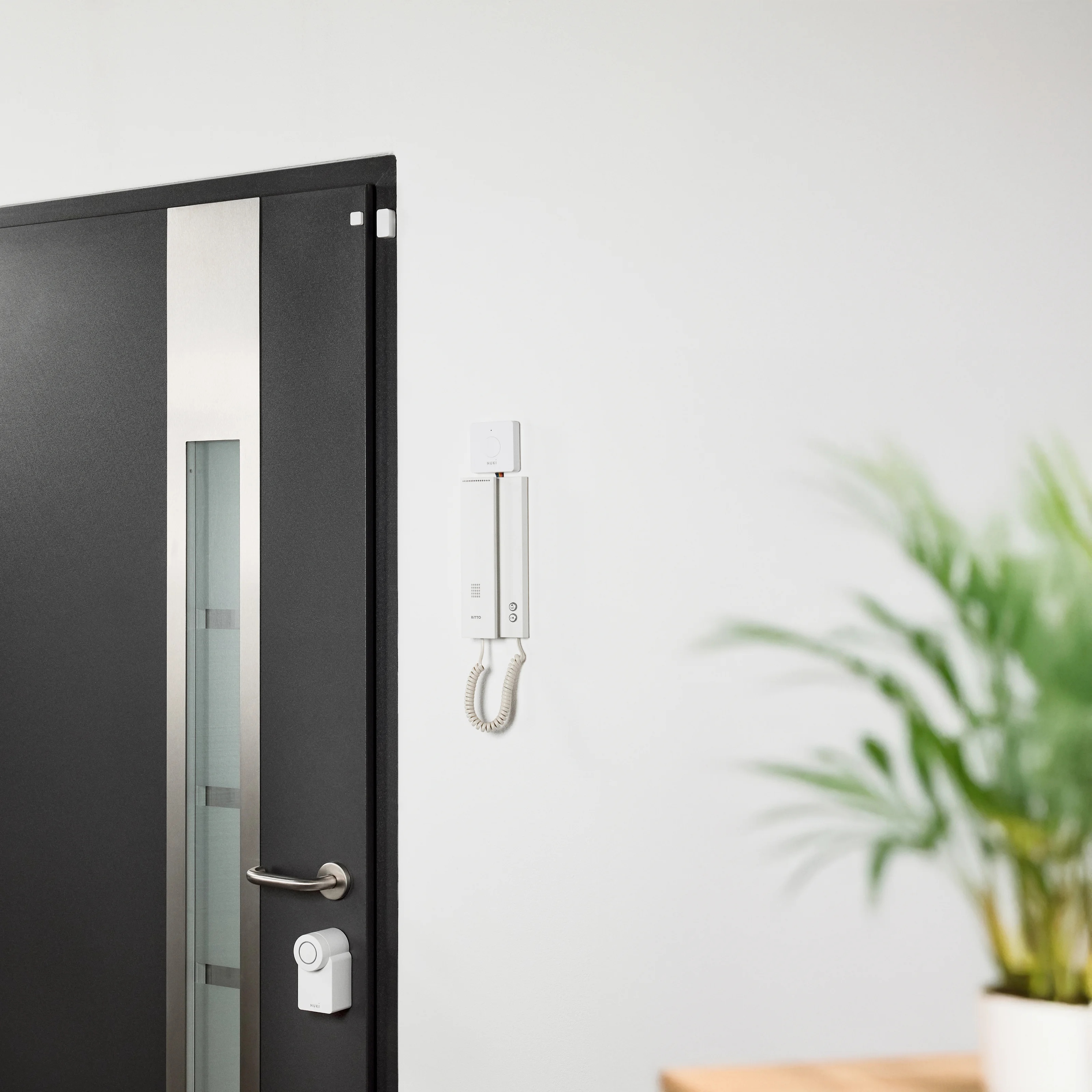 Nuki Smart Lock, Door Sensor, and Opener installed on a modern front door and intercom.