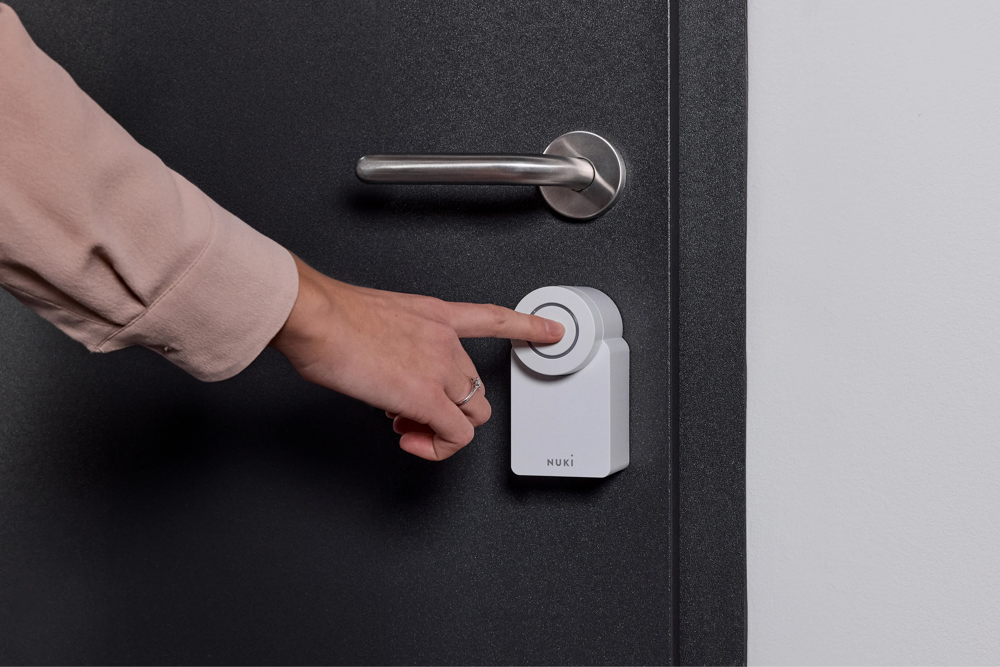 Person unlocking the door by pressing the Nuki Smart Lock Go – keyless, smart access.