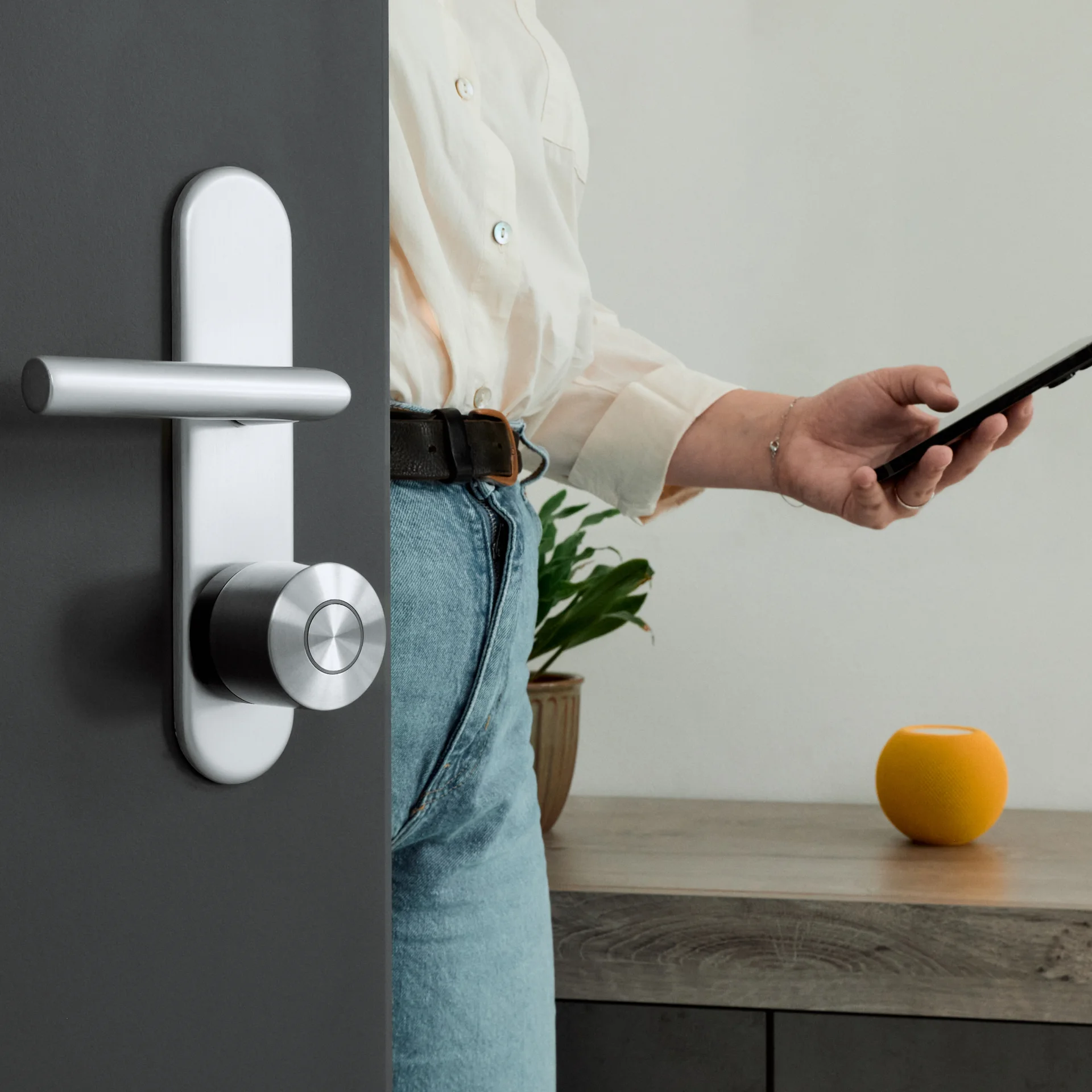 Person unlocking a door with the Nuki Smart Lock using a smartphone, shown from inside the room.