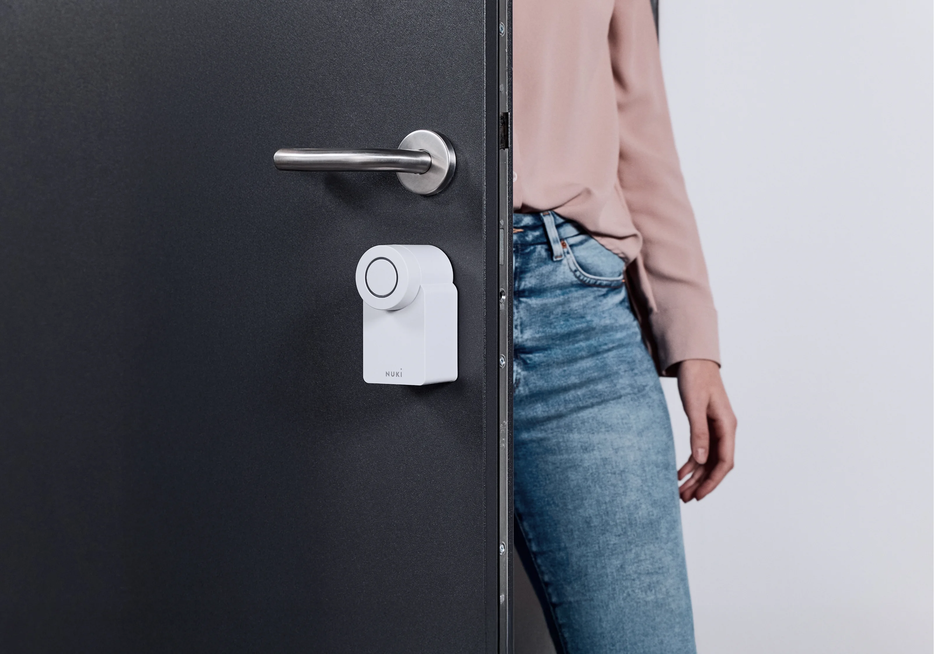 Woman next to a door with Nuki Smart Lock Go – smart access with minimalist design.