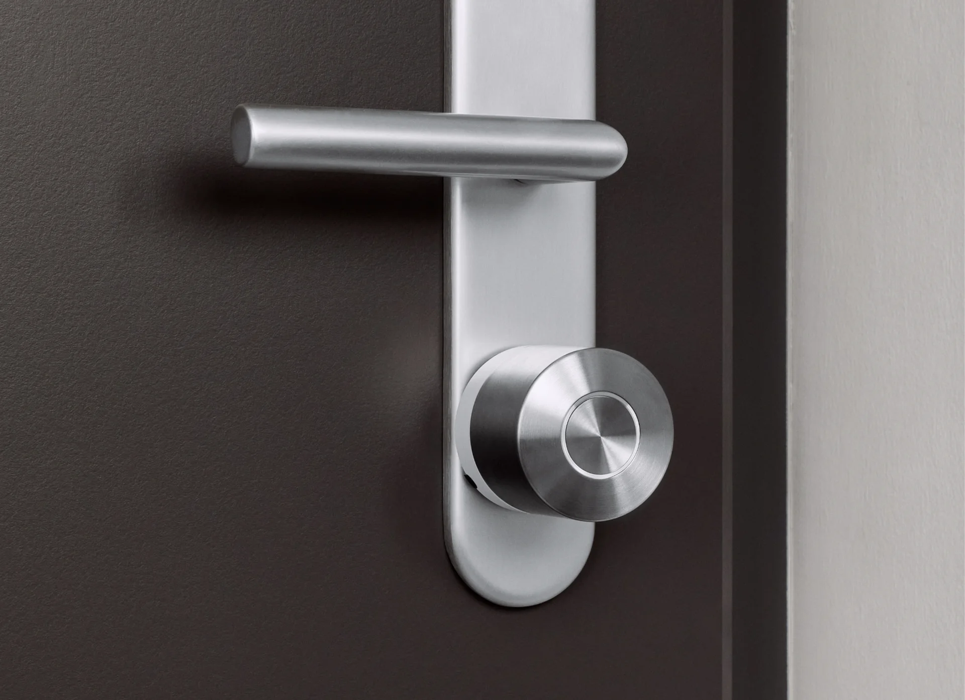 The Nuki Ultra is mounted on the inside of a door, below a silver door handle.