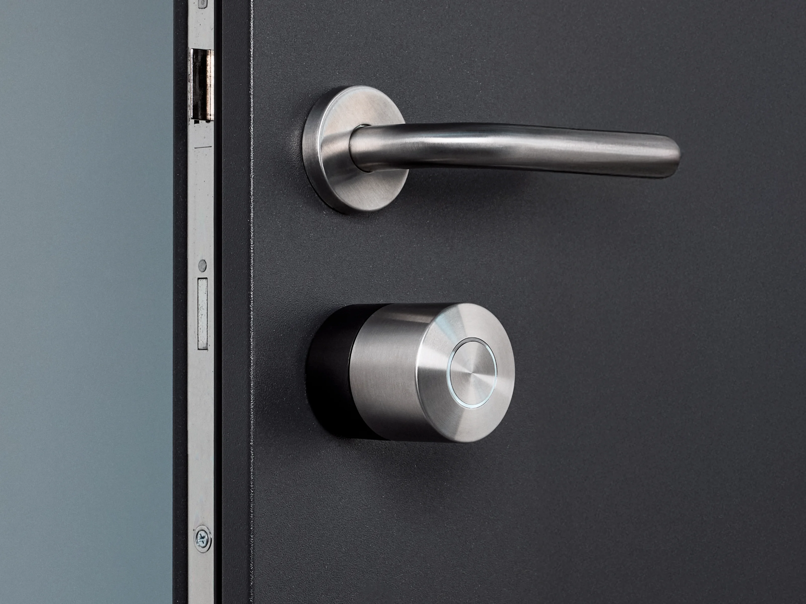 The Nuki Smart Lock Pro with the black ring mounted on a dark door with silver hardware.