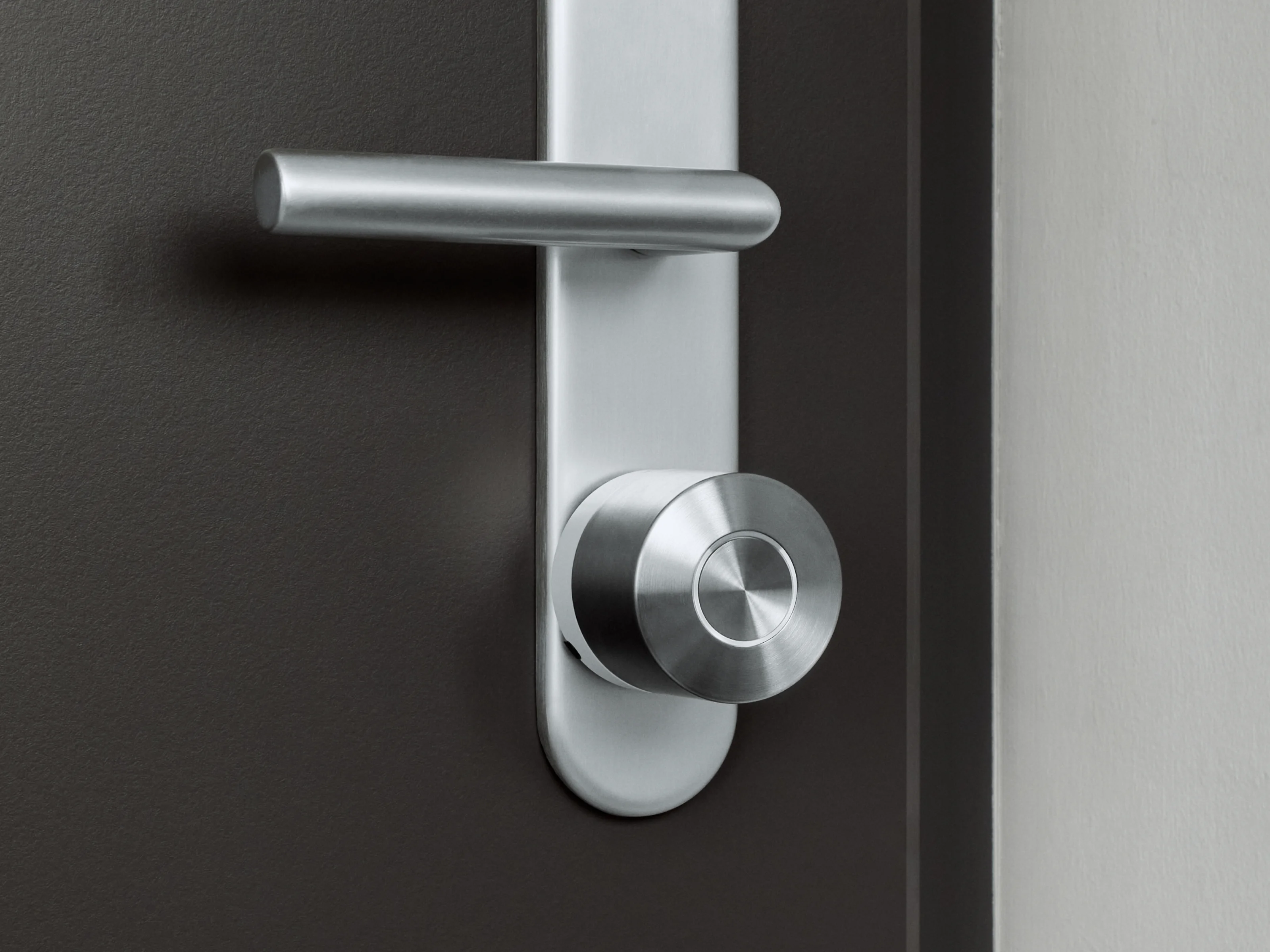 The Nuki Smart Lock Ultra with the white ring mounted on a dark door with silver hardware.