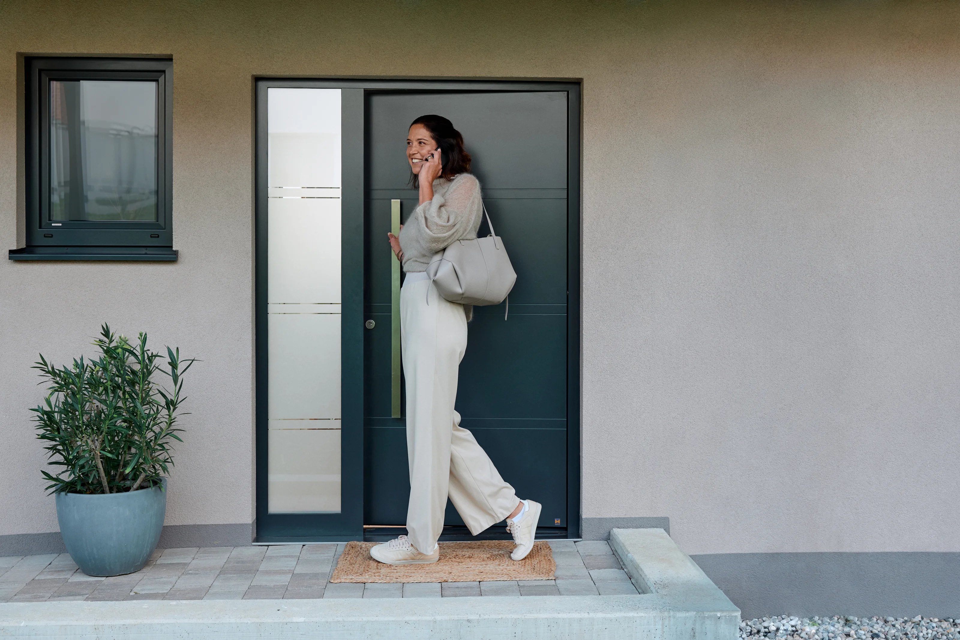 Woman entering her home thanks to Auto Unlock while speaking on the phone.