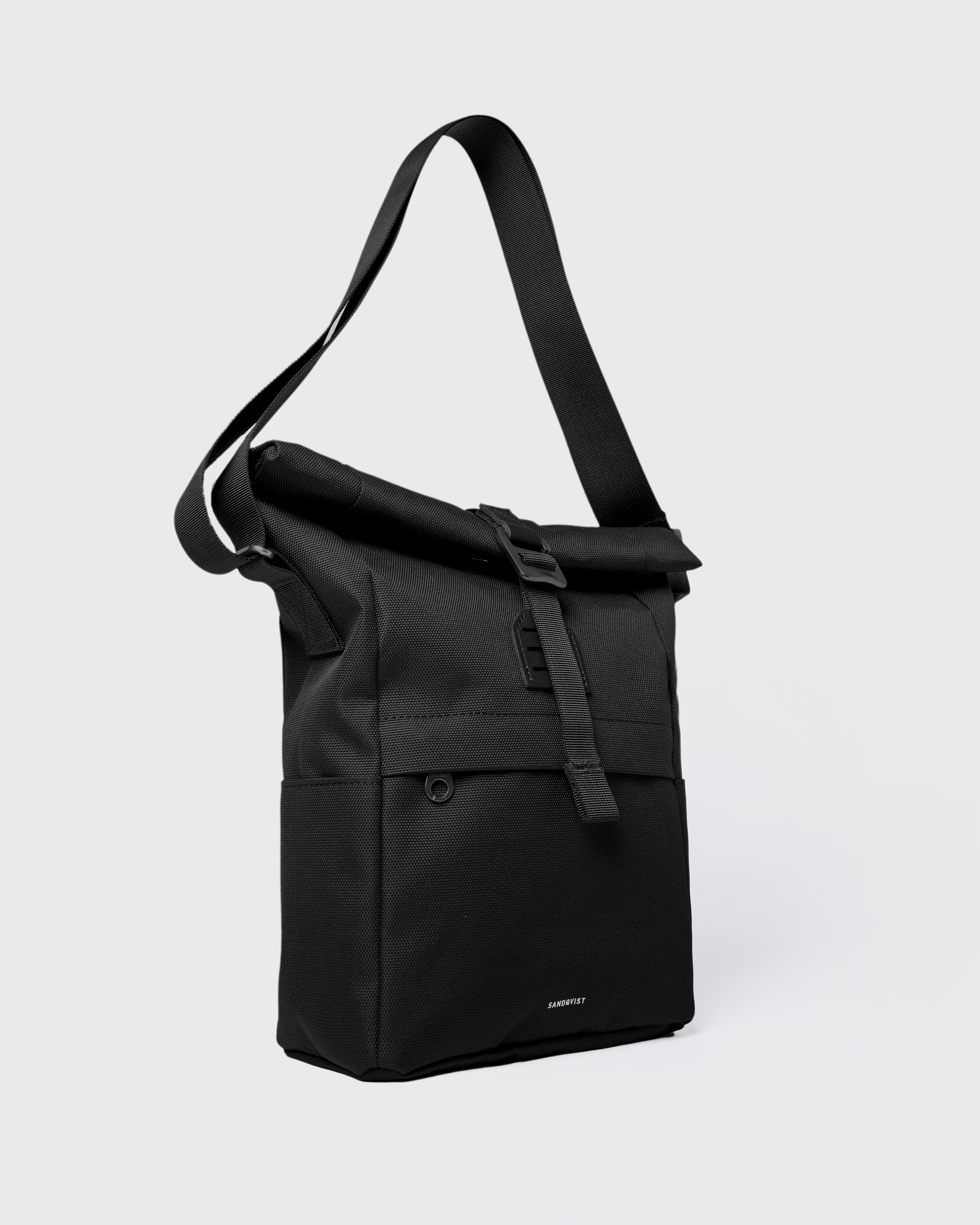 Sandqvist ICON Sacoche in black, side view with shoulder strap, rolltop closure, side slip pocket and front zipper pocket.