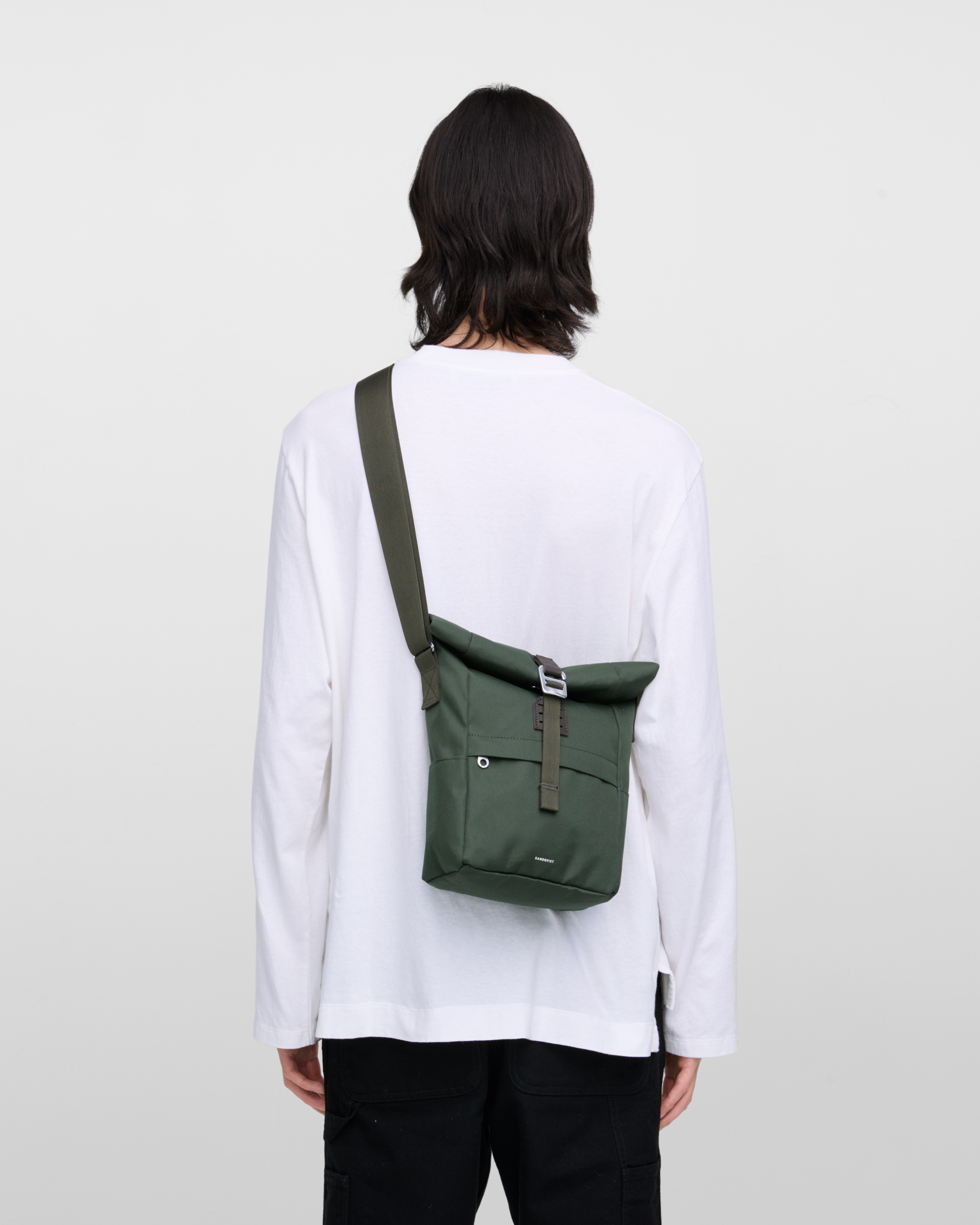 Sandqvist ICON Sacoche in Dark Green, carried crossbody  on a male model. View of upper body from behind showing size and fit of the bag.
