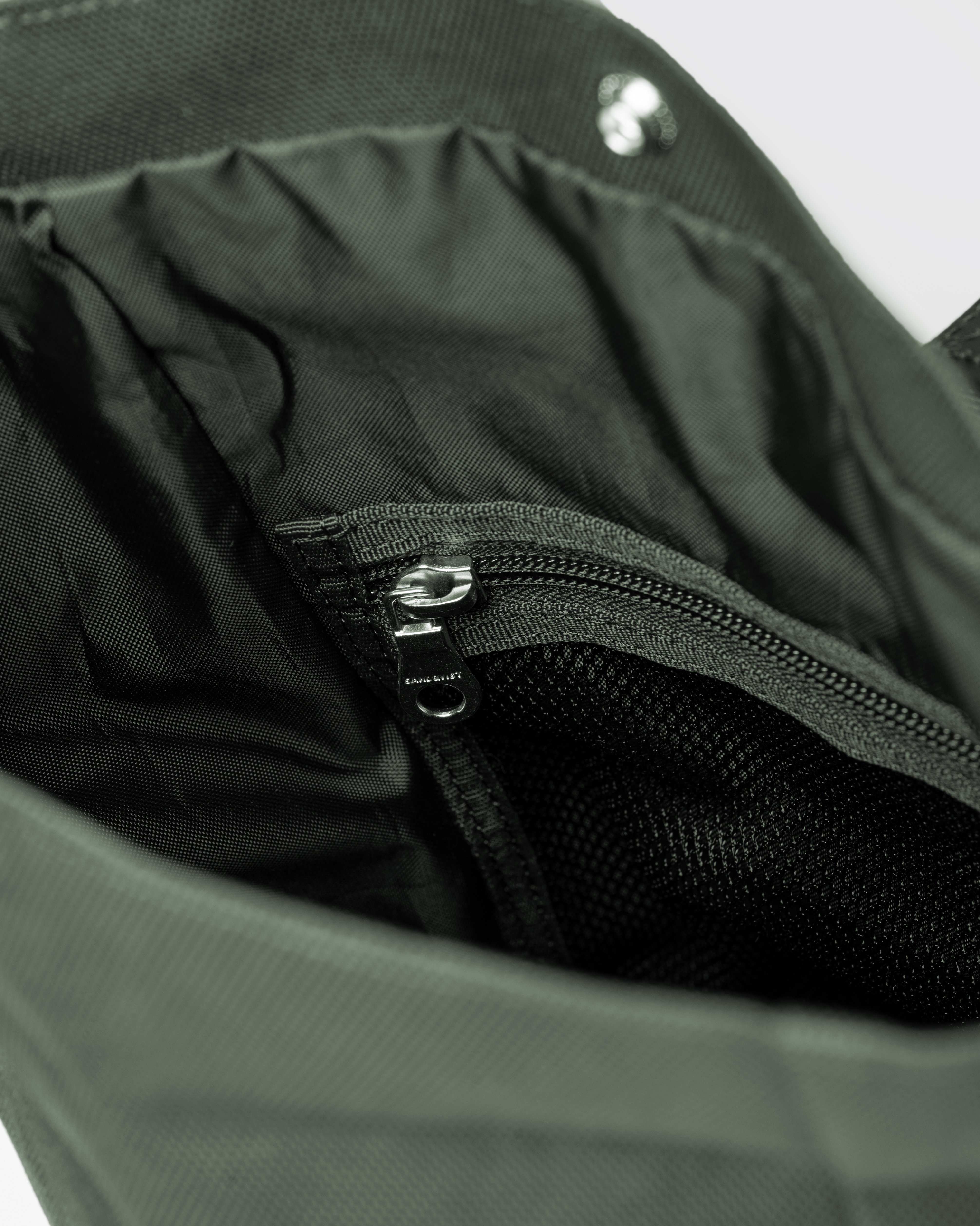 Inside view of main compartment with press button and zipper mesh pocket for Sandqvist ICON Sacoche in Dark Green. 