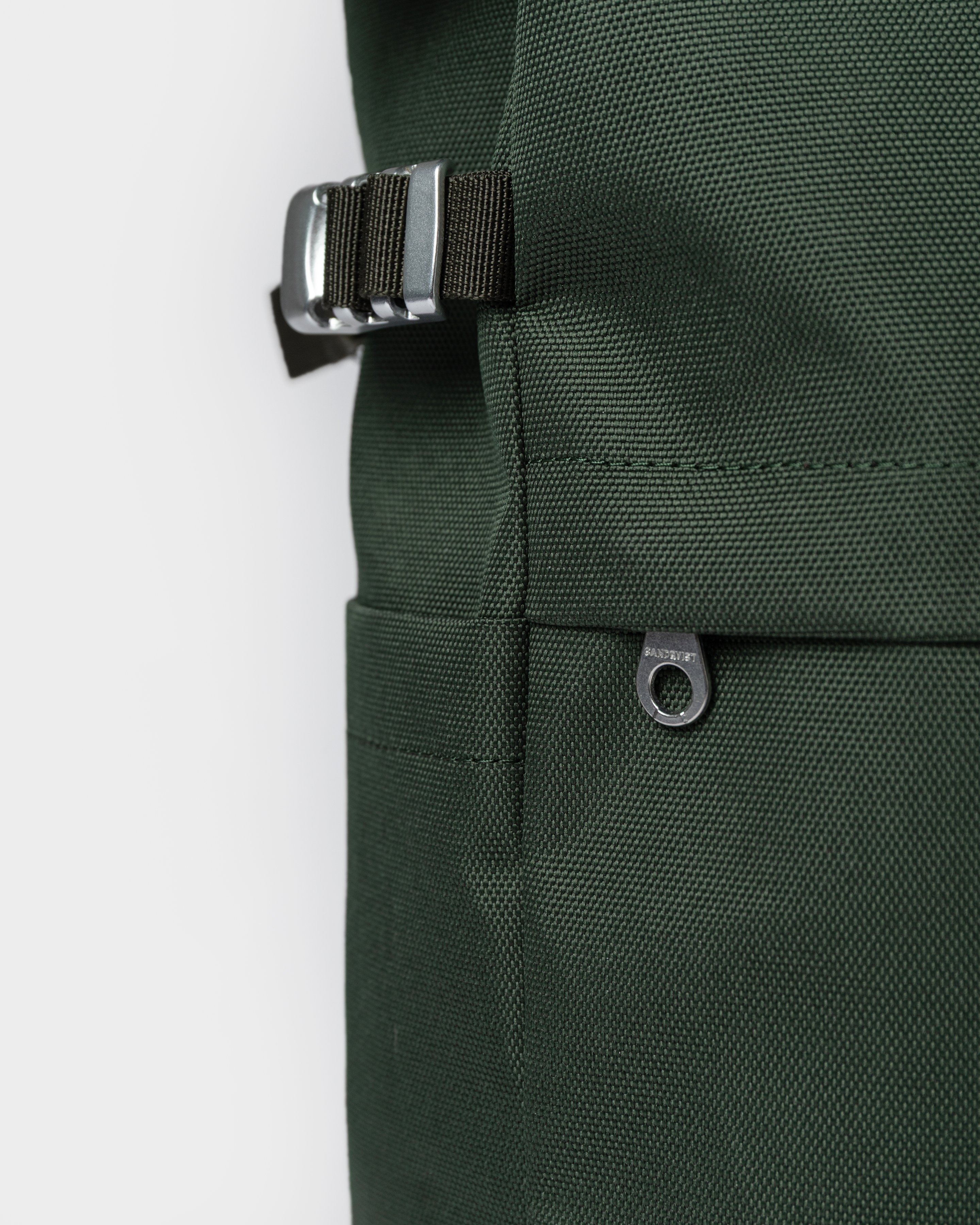 Close up view of adjustable strap, side slip pocket and outer zipper pocket on the backpack Sandqvist ICON Rolltop Backpack M 14" in dark green.