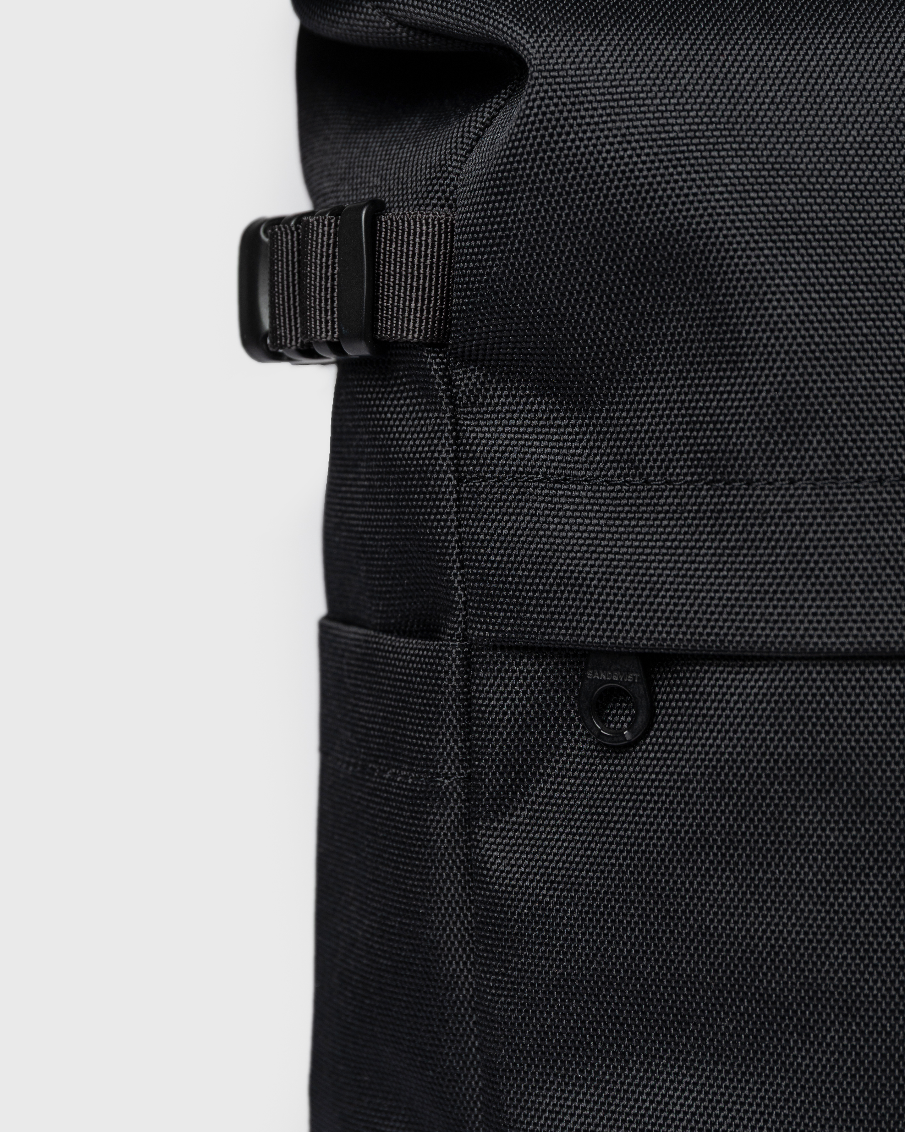 Close up view of adjustable strap, side slip pocket and outer zipper pocket on the backpack Sandqvist ICON Rolltop Backpack M 14" in black.
