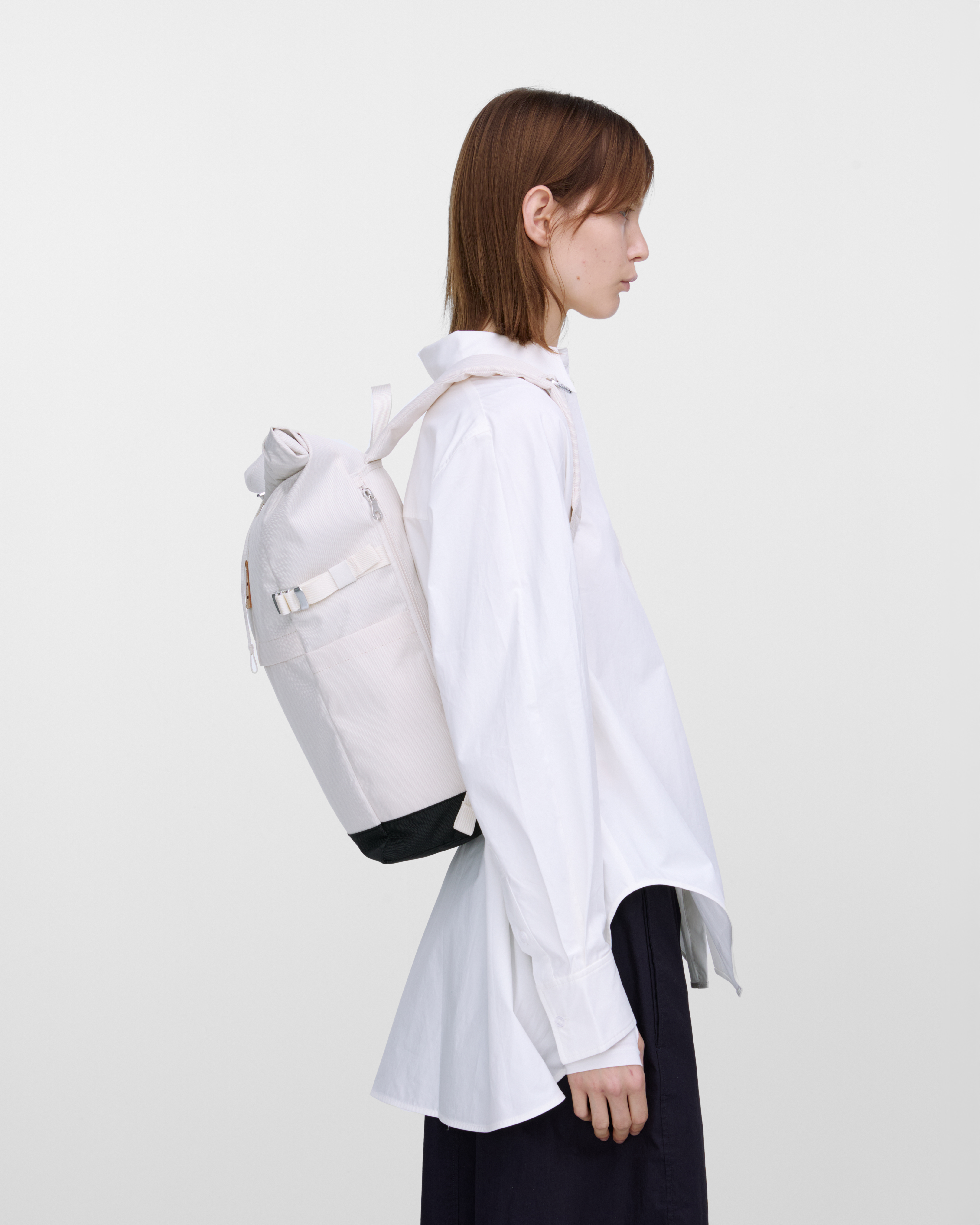 Mannequin féminin portant un sac à dos Sandqvist ICON Rolltop Backpack M blanc, vue de profil montrant la coupe et la taille. 