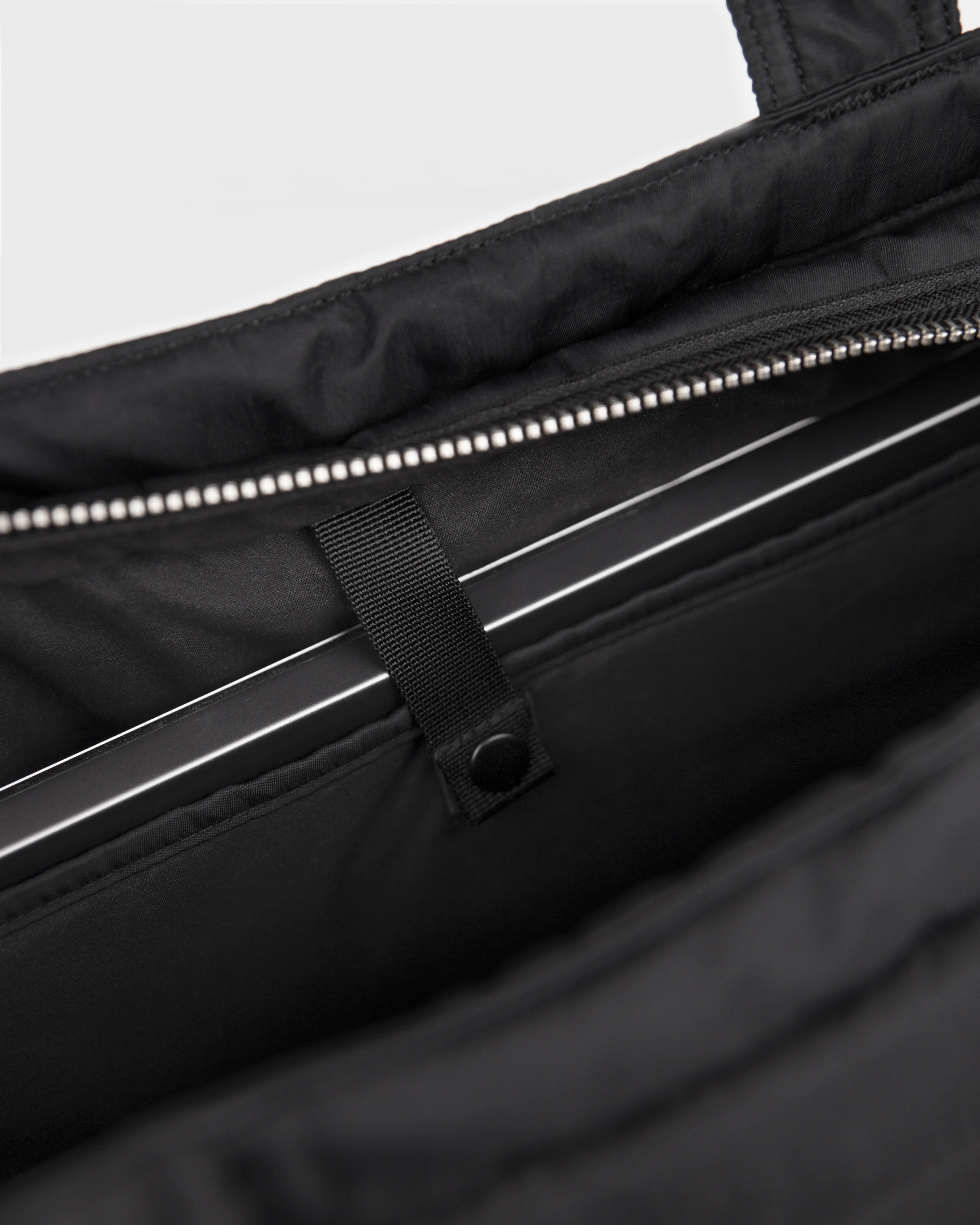 Sandqvist Curve Tote Bag, black. Inside view, laptop compartment with snap button.