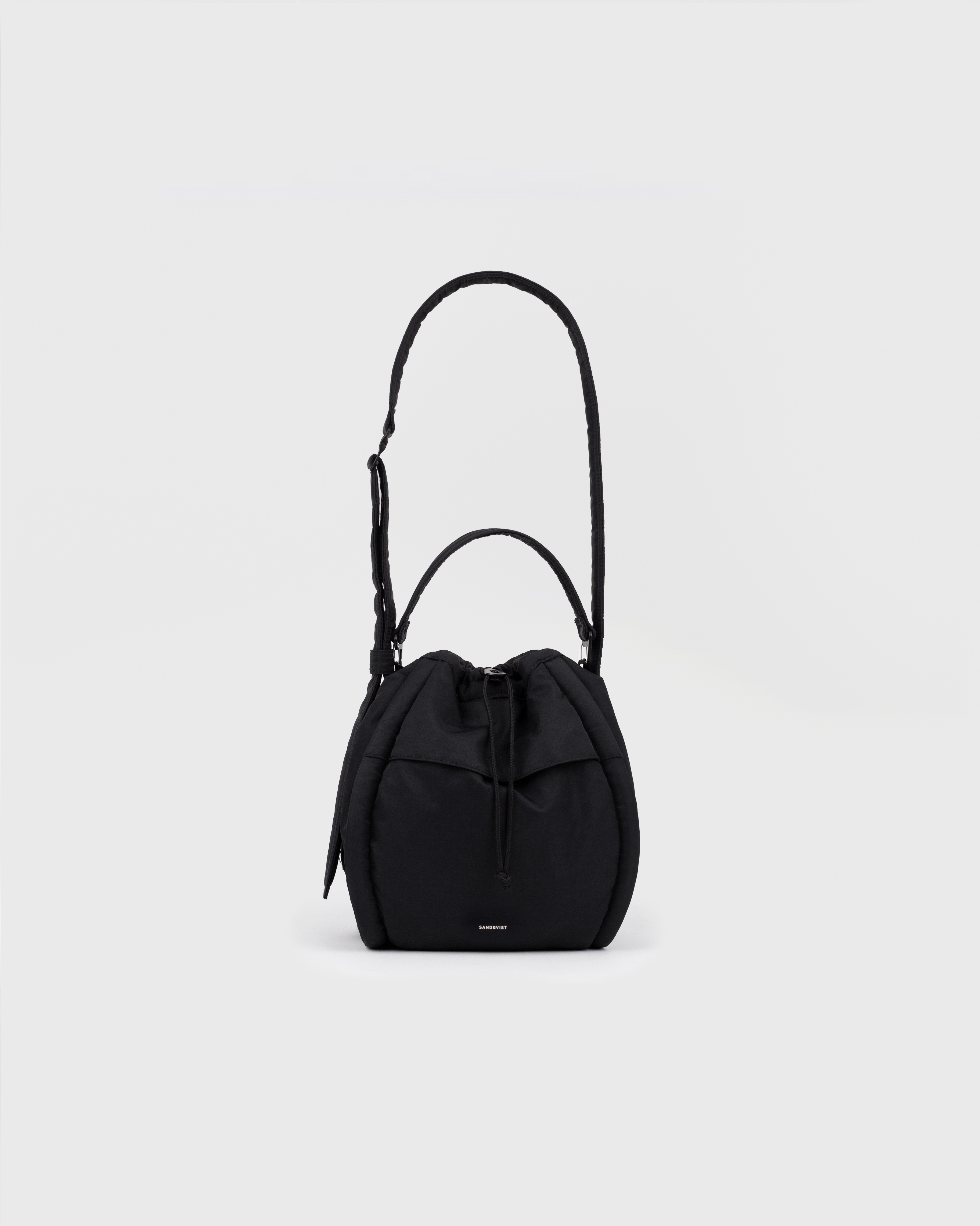 Front view of Sandqvist Curve Bucket Bag, black, in a standing position with the strap and handle showing.