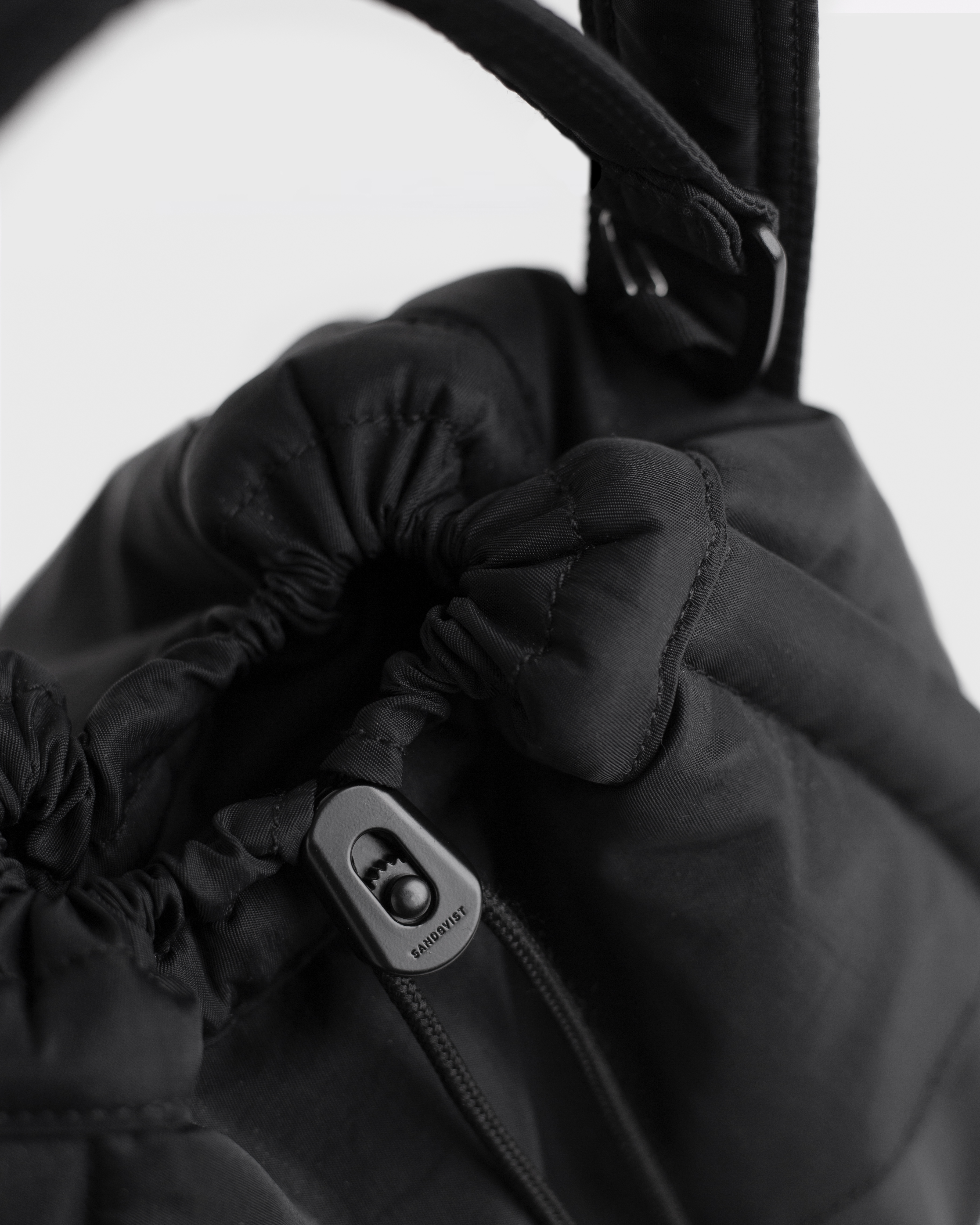 Close-up of one side of the adjuster of Sandqvist Curve Bucket Bag, black.