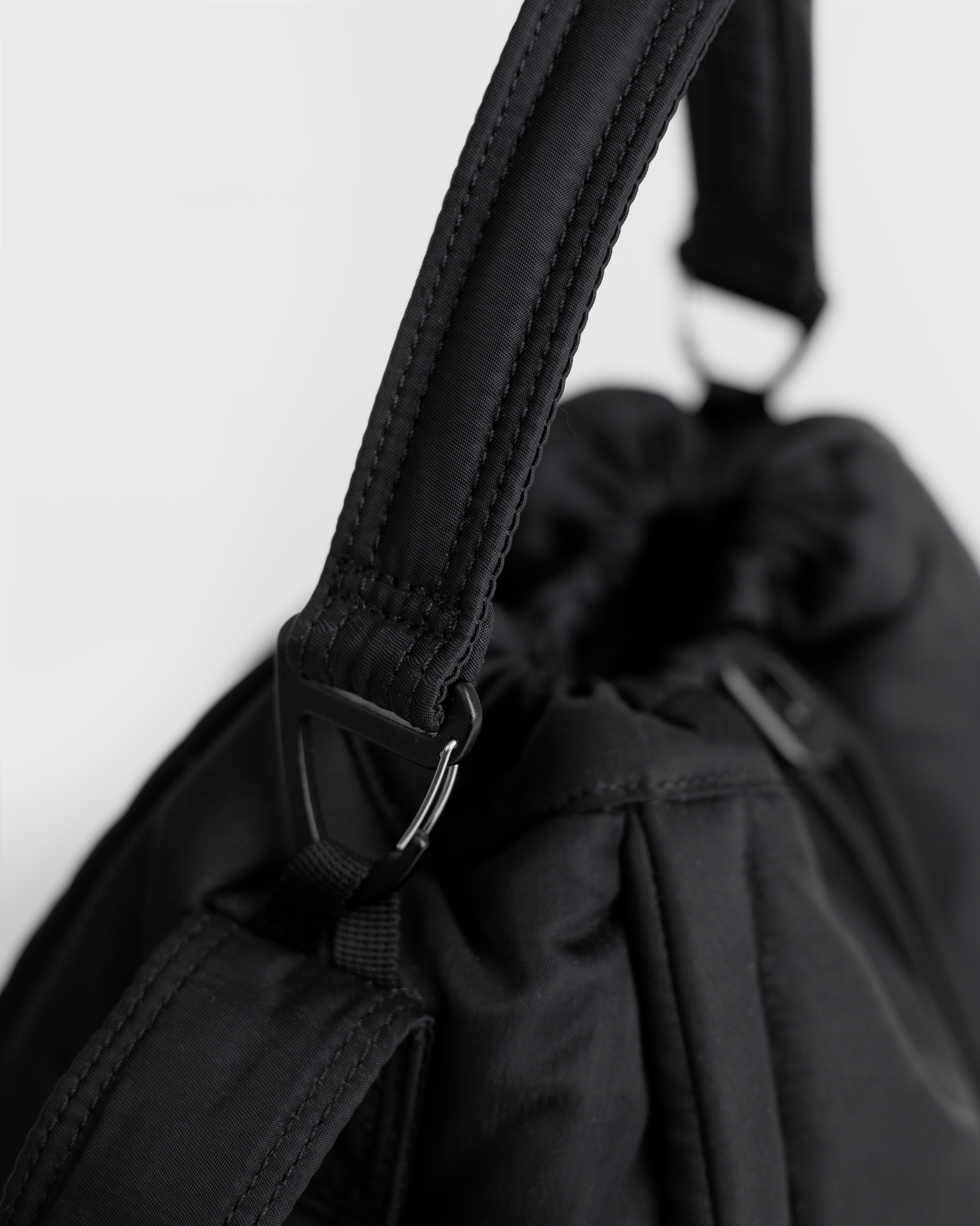 Close-up of one side of the handle of Sandqvist Curve Bucket Bag, black.