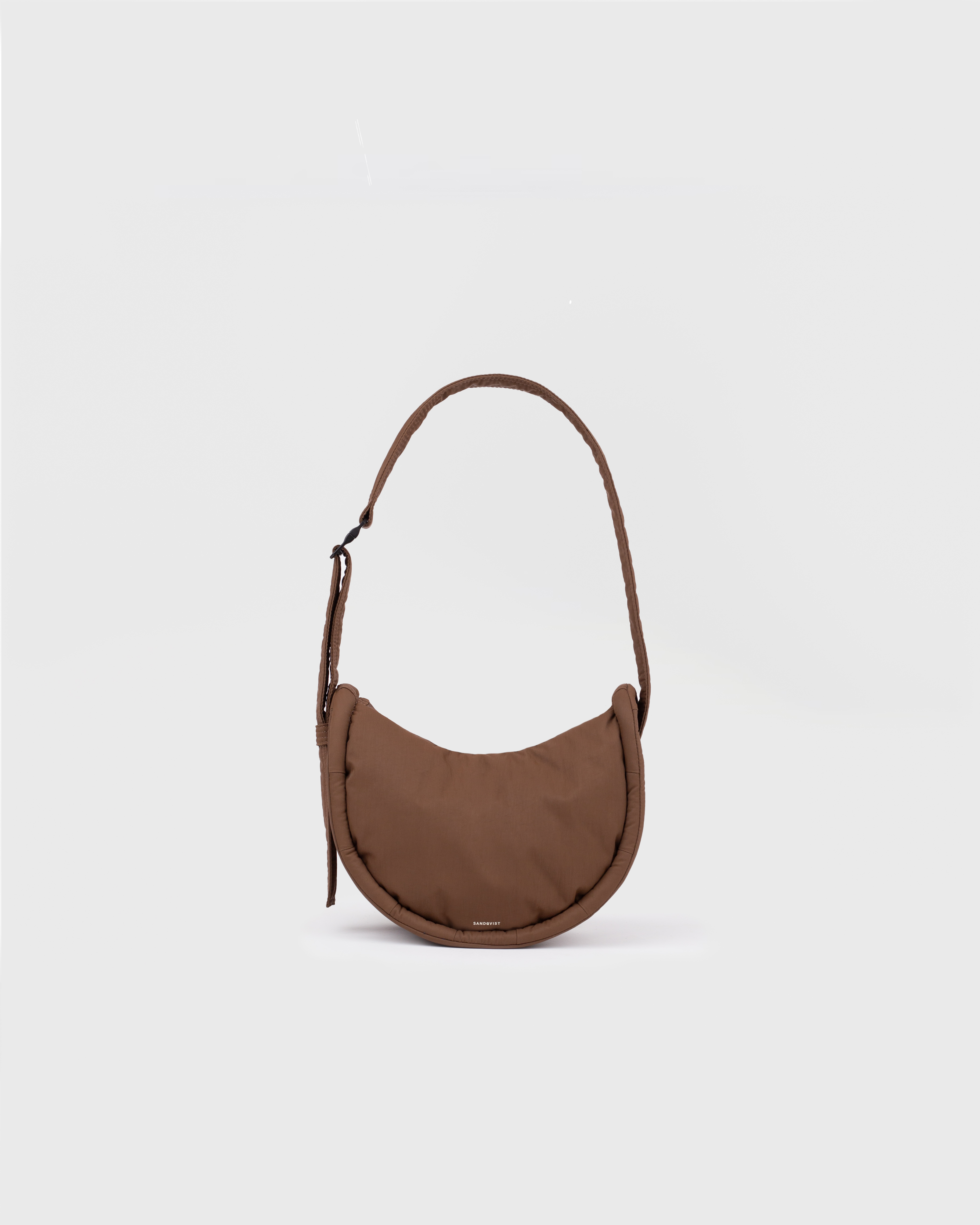 Handbag. Sandqvist Curve Half Moon Bag Mini, brown. Front view, shoulder strap with adjuster.
