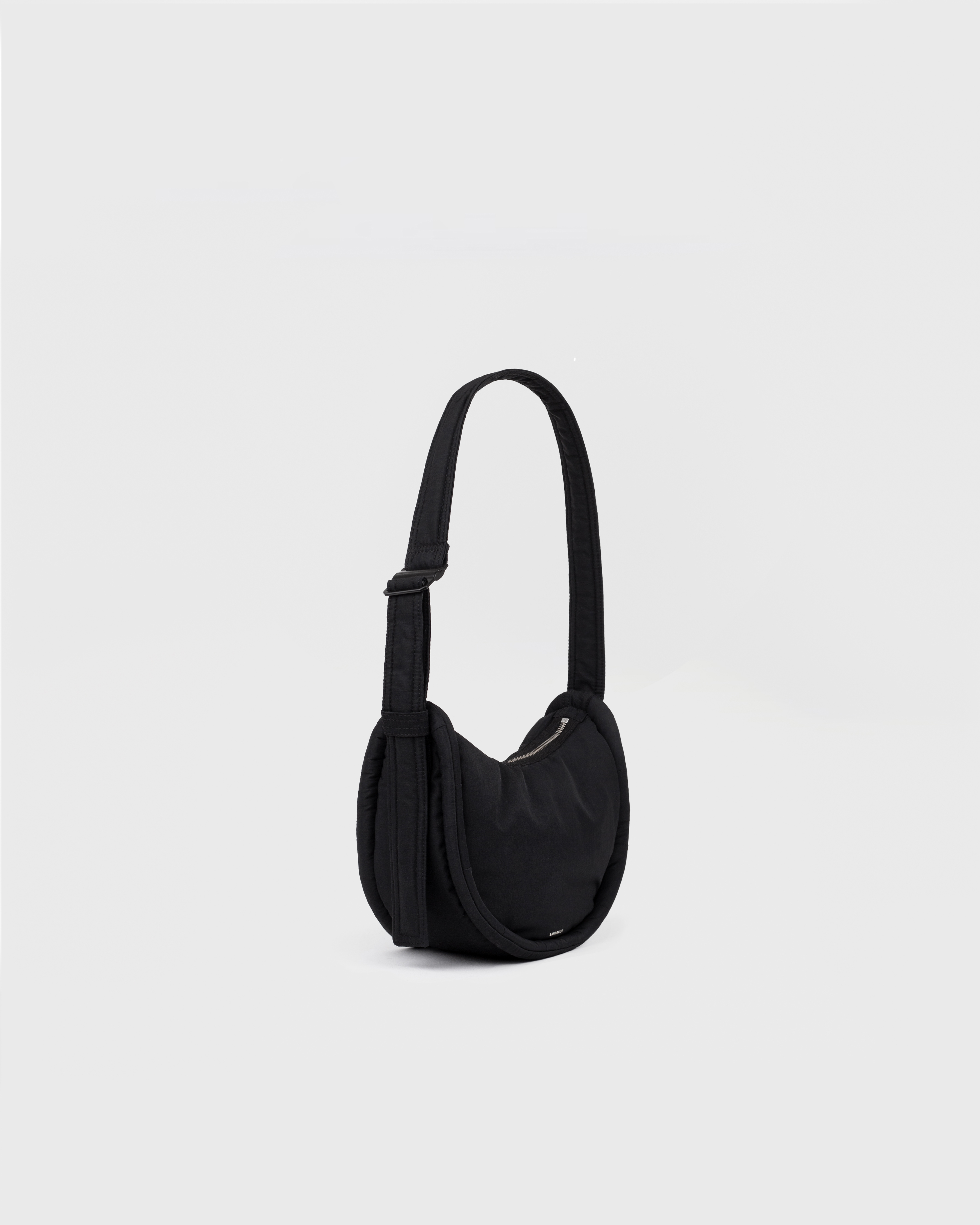 Handbag. Sandqvist Curve Half Moon Bag Mini, black. Side view, shoulder strap with adjuster.