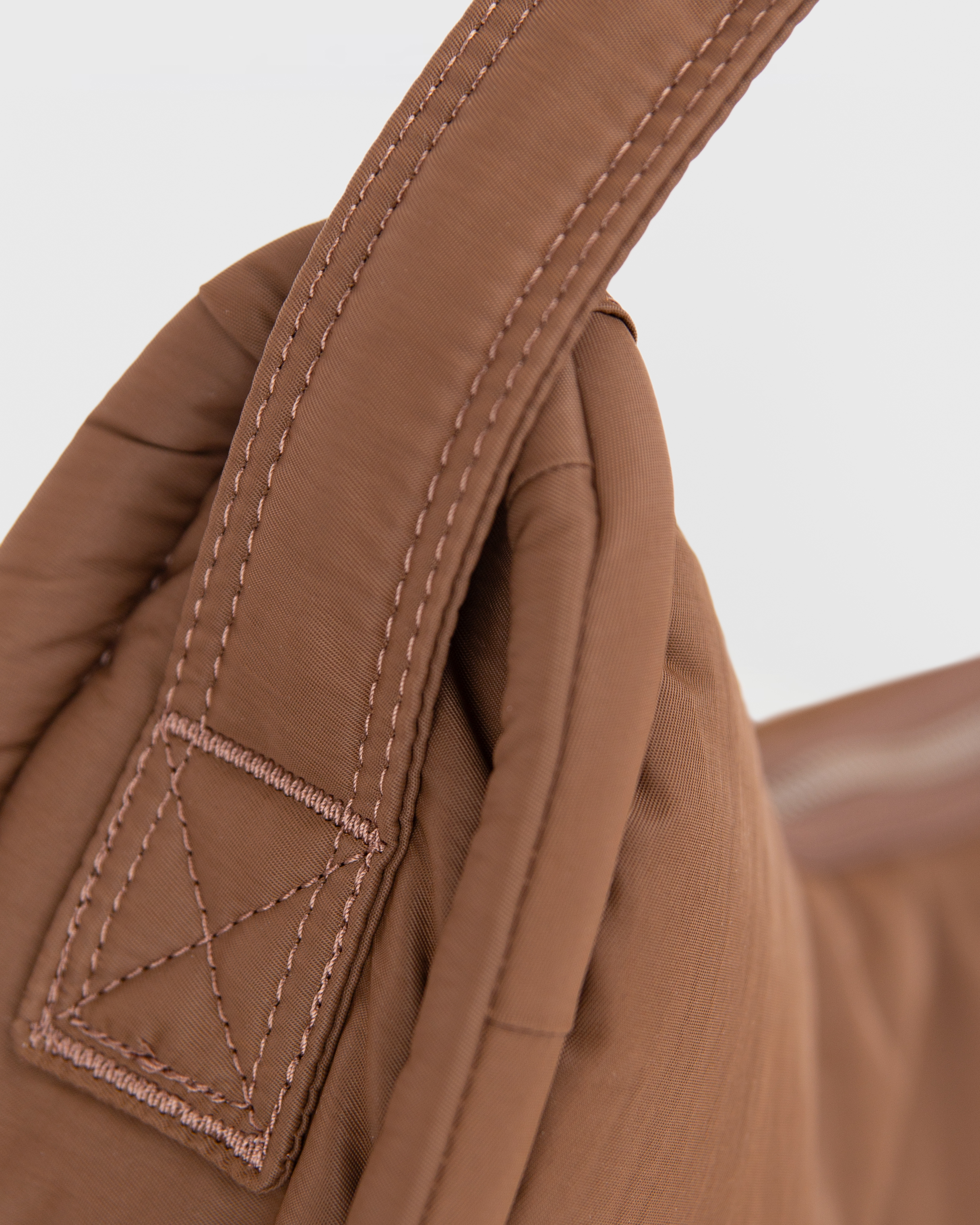 Close-up of the seams of the handle of Sandqvist Curve Half Moon Bag mini, brown.