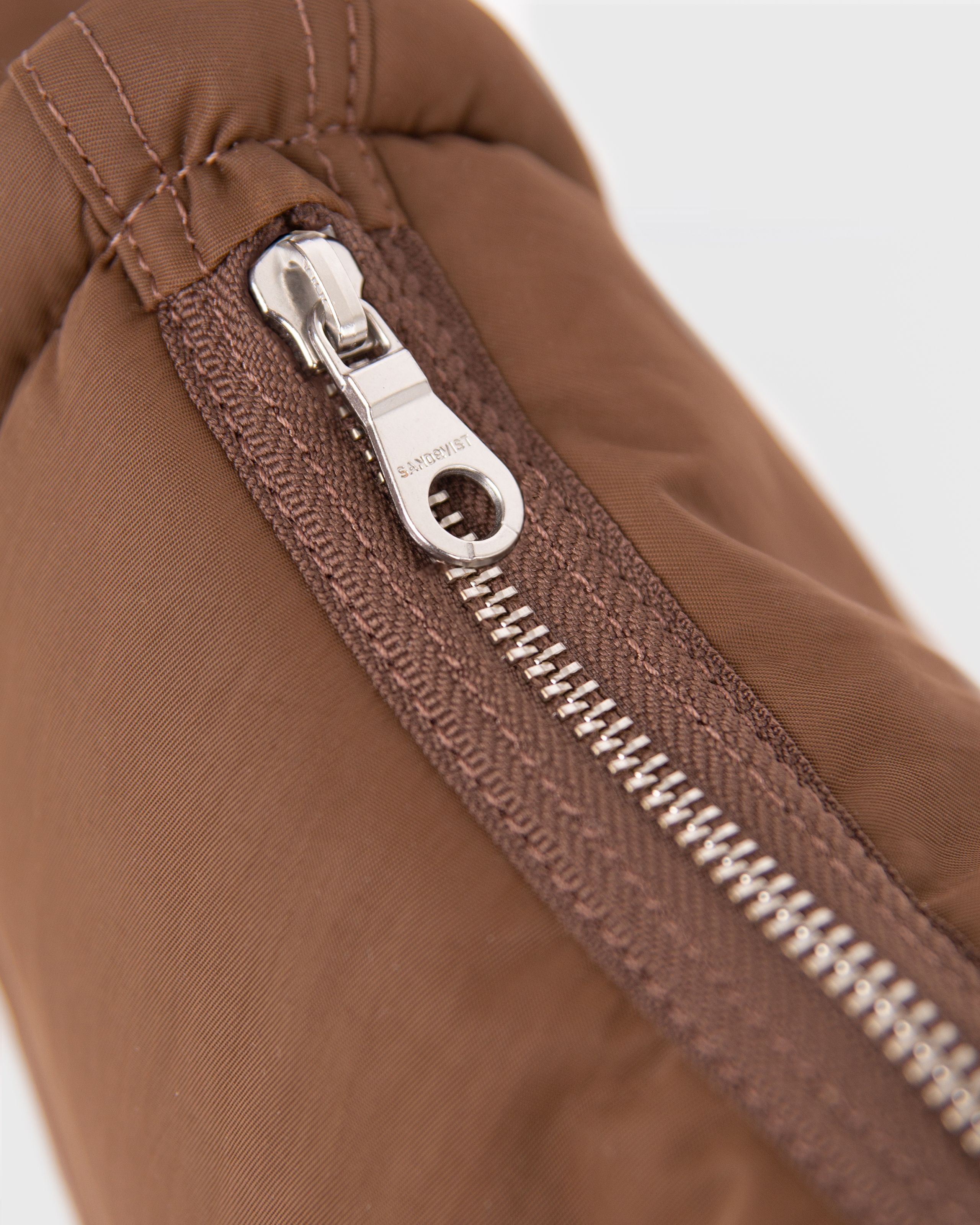 Close-up of the zipper of Sandqvist Curve Half Moon Bag mini, brown.