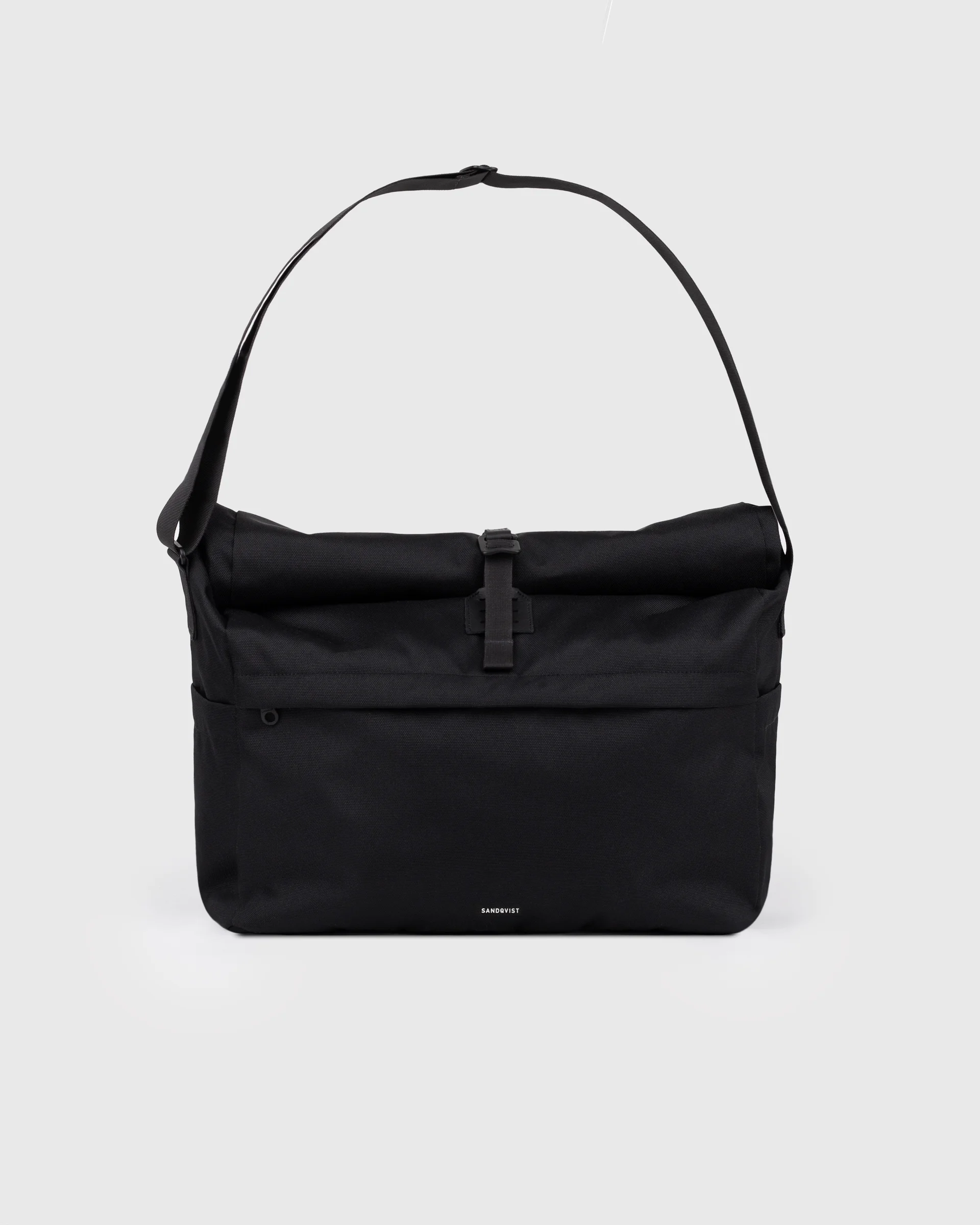 Sandqvist Icon Messenger Bag, schwarz. Vorderansicht, Schnalle und Schulterriemen.