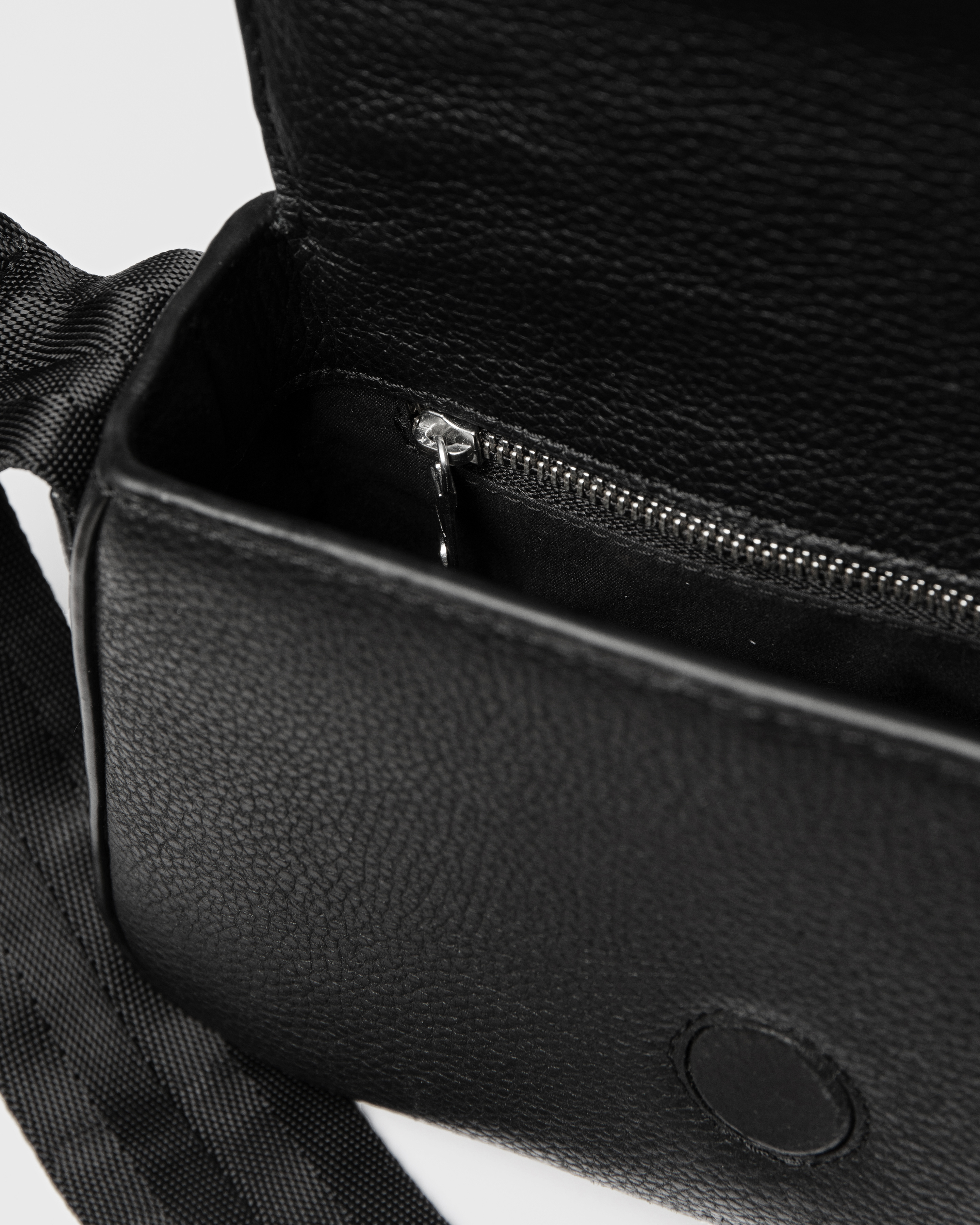 View of the inside of Sandqvist Agile Handle Crossbody Bag, black, with one zippered pocket and the strap showing.