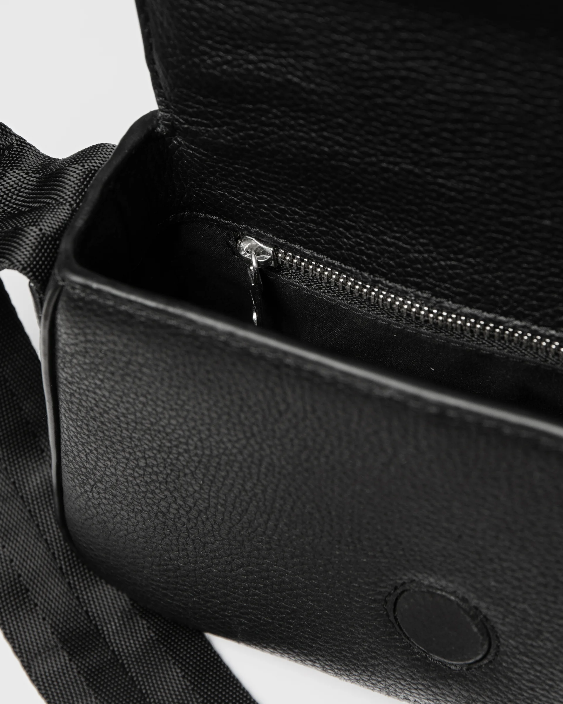 View of the inside of Sandqvist Agile Handle Crossbody Bag, black, with one zippered pocket and the strap showing.