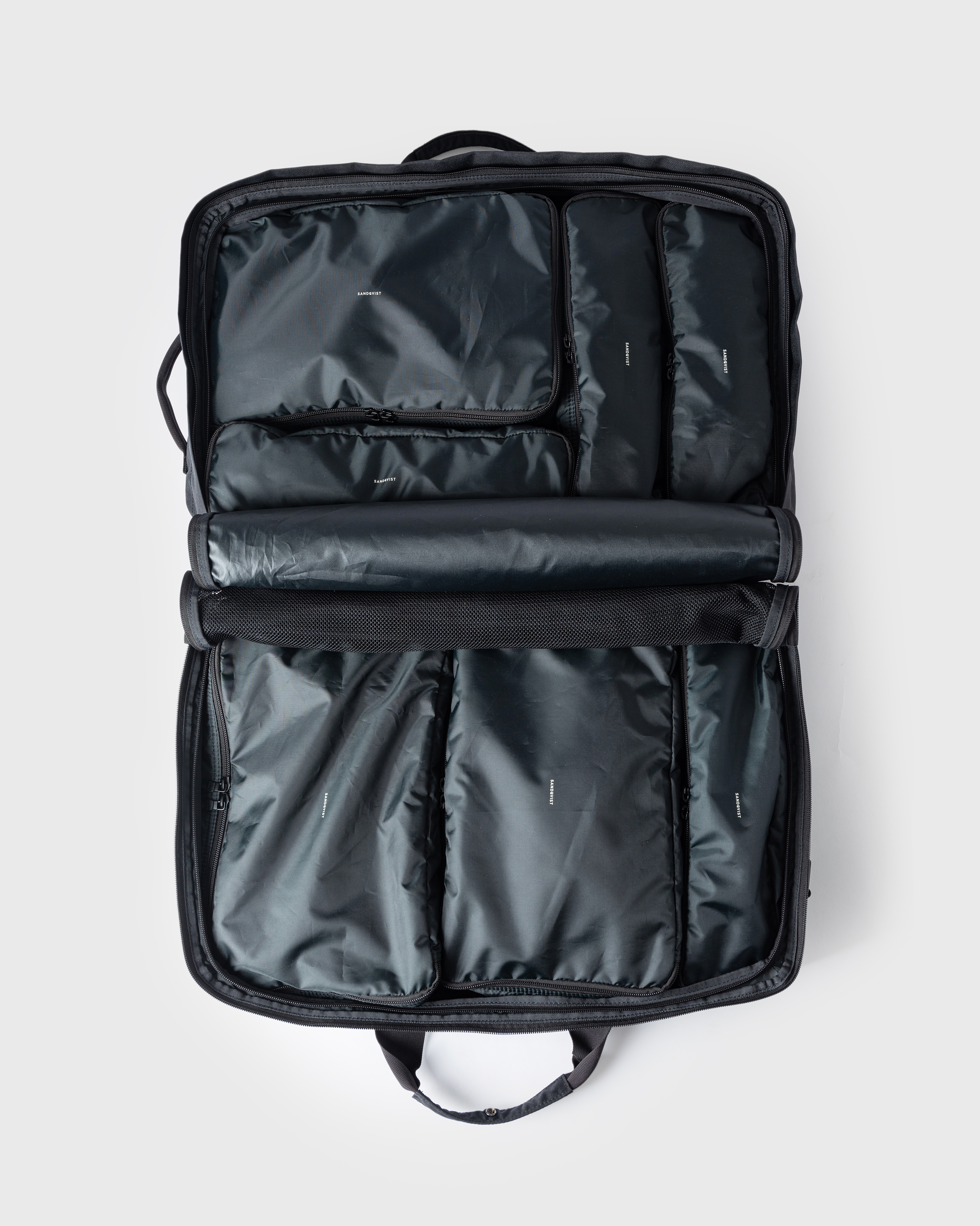 Sandqvist GO 3-way Bag M fully opened. Top view showing the bag filled with four packing cubes on one side and three packing cubes on the other side.