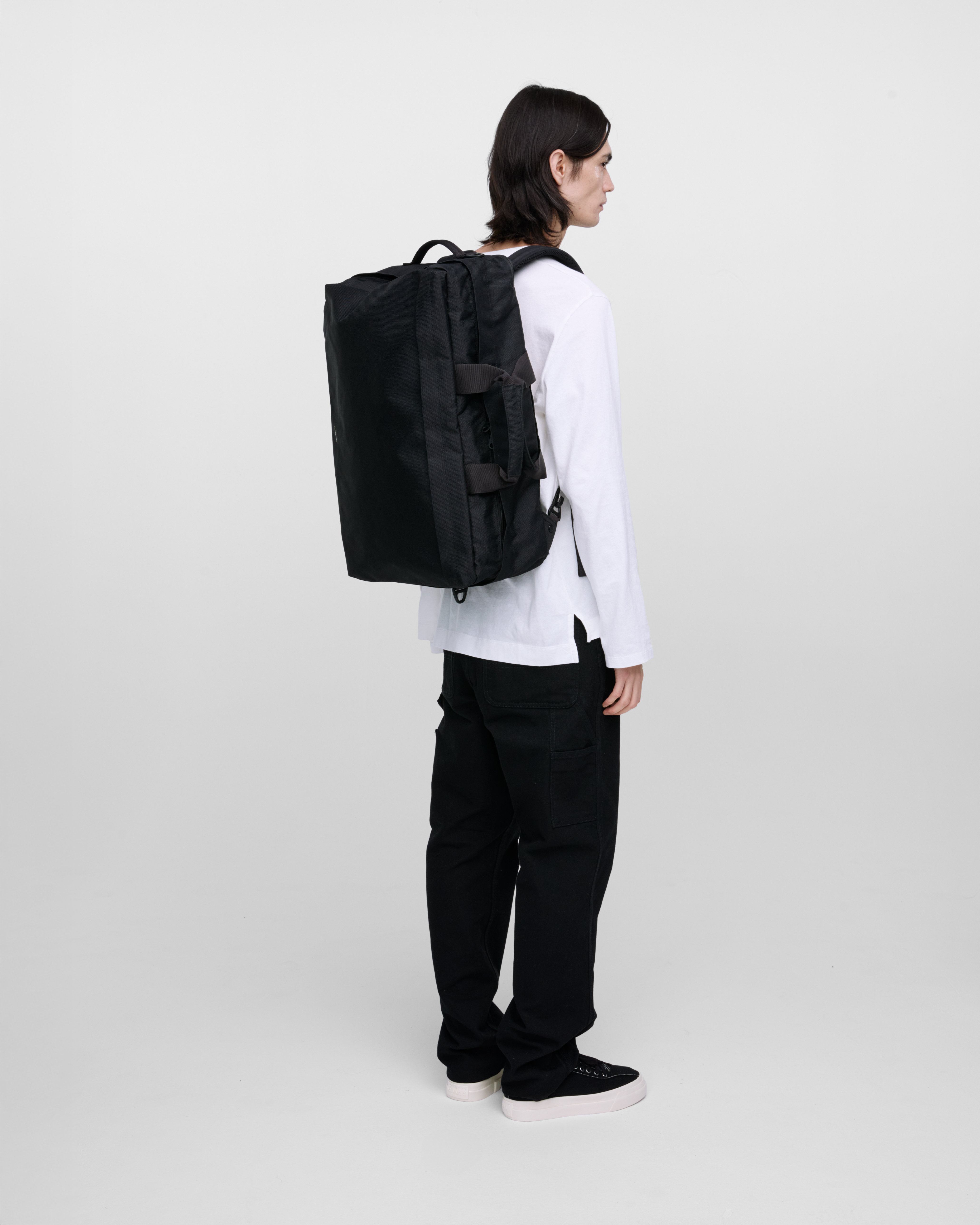 Male model wearing Sandqvist GO 3-way bag L, black. Back view, wearing the bag on the back.