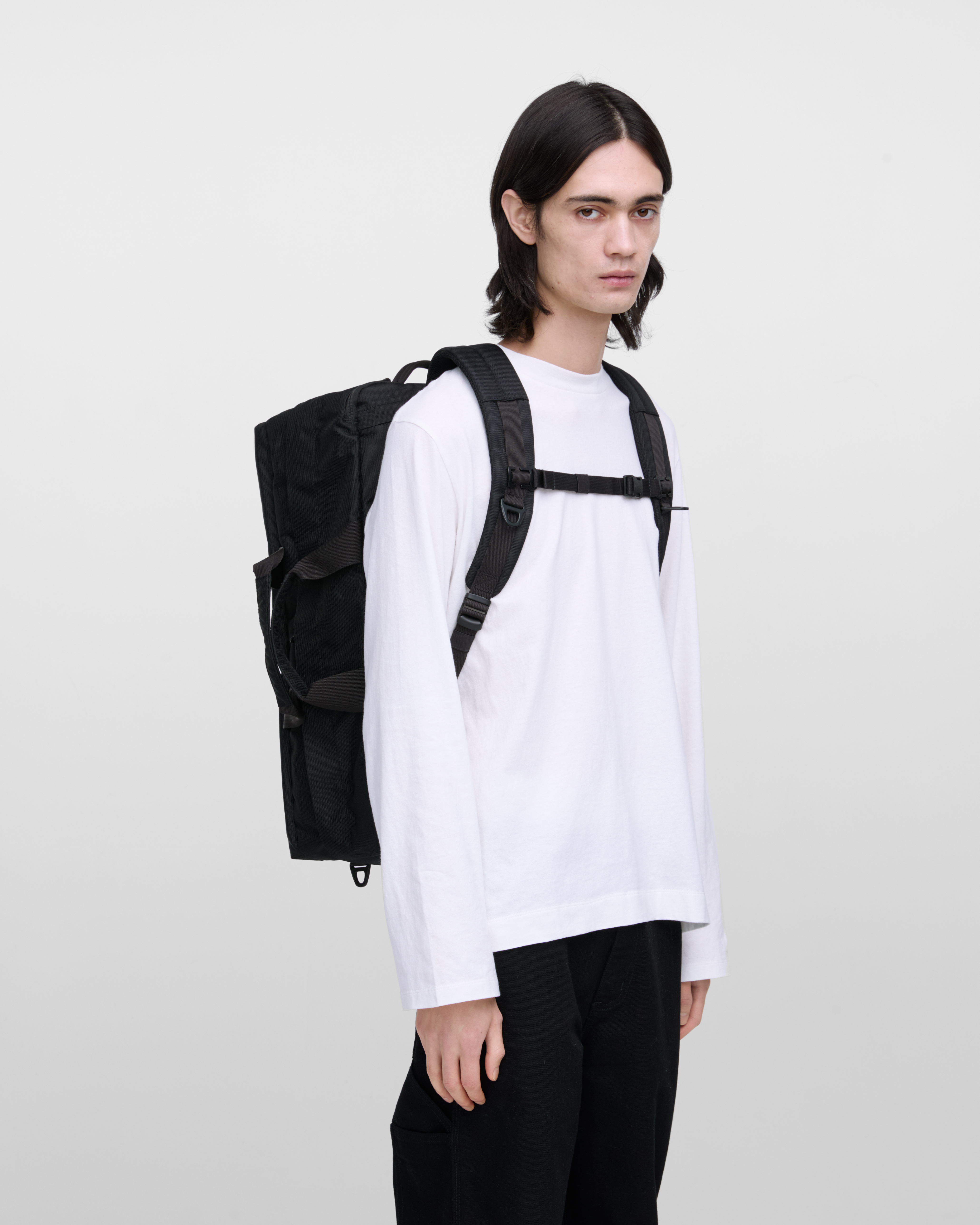 Male model wearing Sandqvist GO 3-way bag L, black. Front view, wearing the bag on the back.
