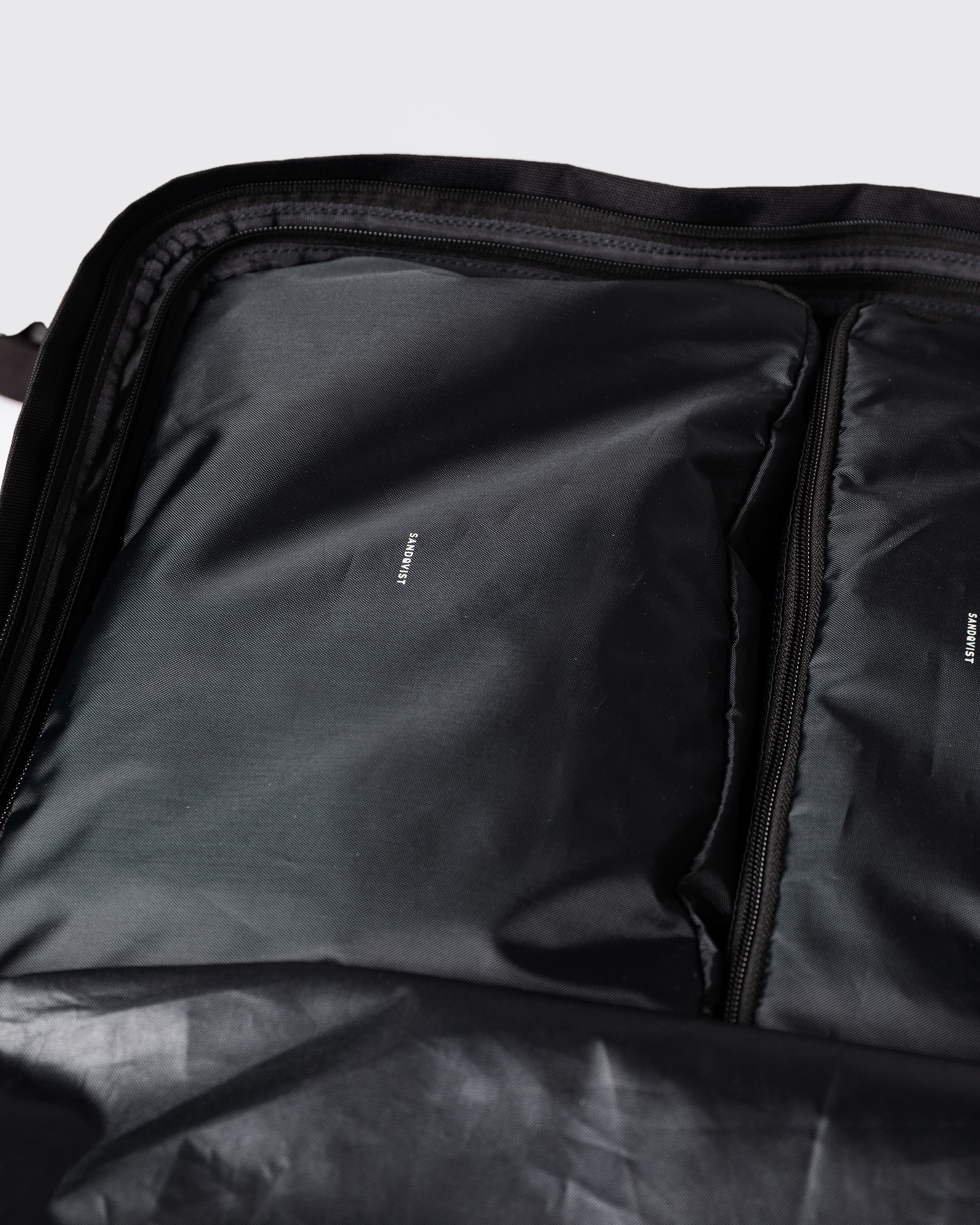 Svart packningskub inuti en svart väska. Närbild som visar Sandqvist ITEMS Packing Cube M i svart inuti Sandqvist GO 3-way Bag.