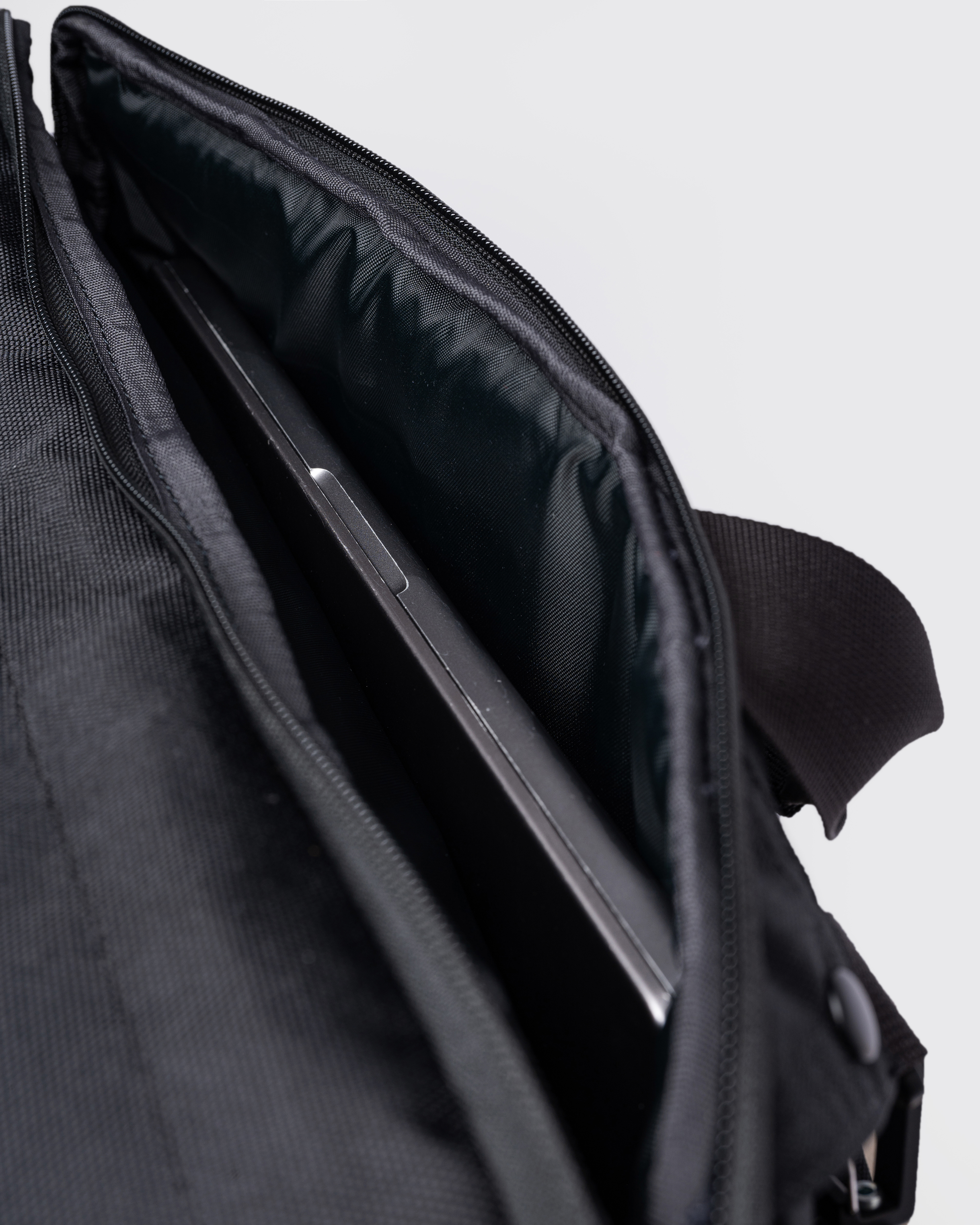 GO 3-Way Bag M, black. Inside view of the pocket with a laptop inside.