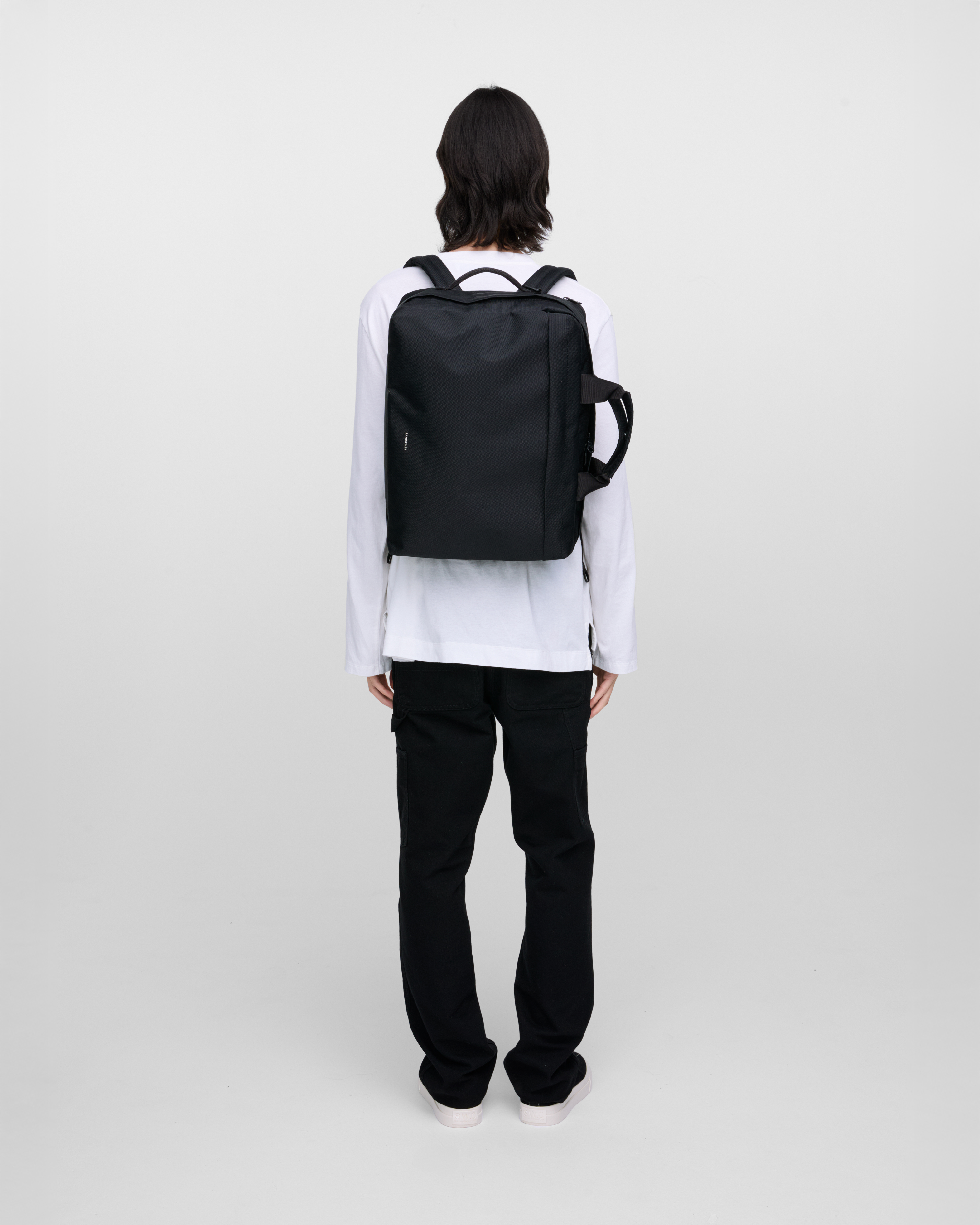 Male model wearing Sandqvist GO 3-Way Bag M, black. Back view, wearing the bag on the back.