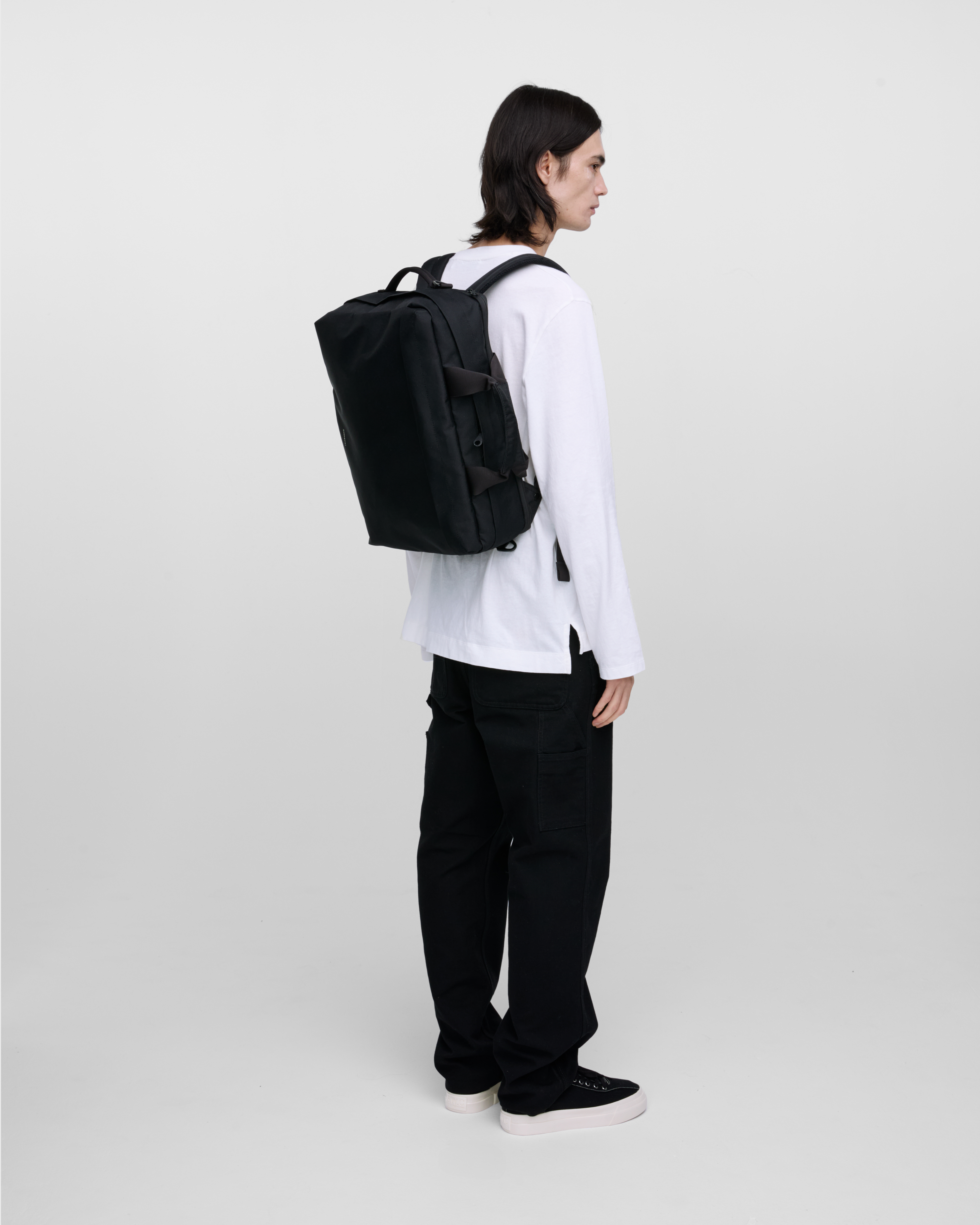 Male model wearing Sandqvist GO 3-Way Bag M, black. Back view, wearing the bag on the back.