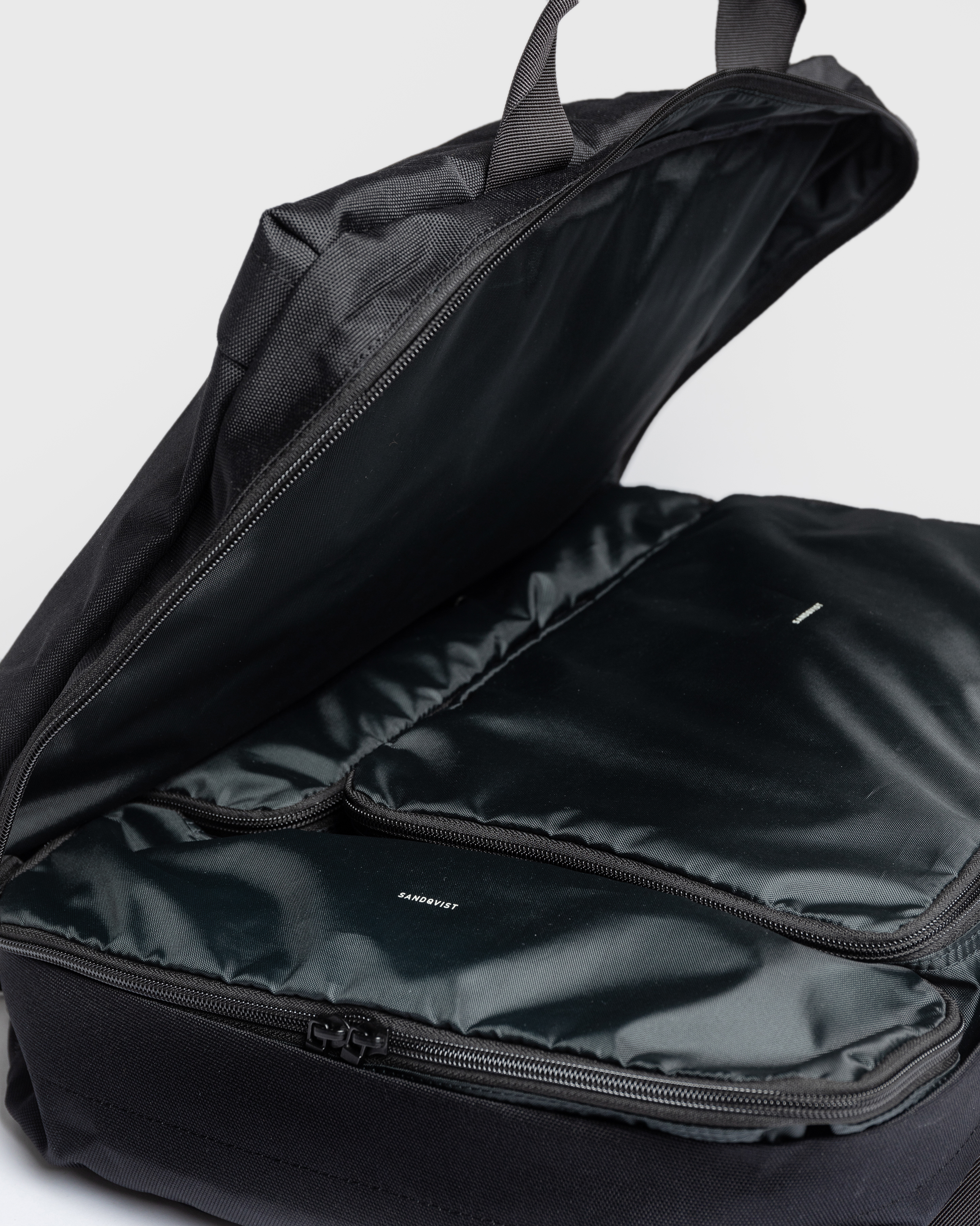 Sandqvist GO 3-way Bag M with opened lid with three packing cubes inside. 