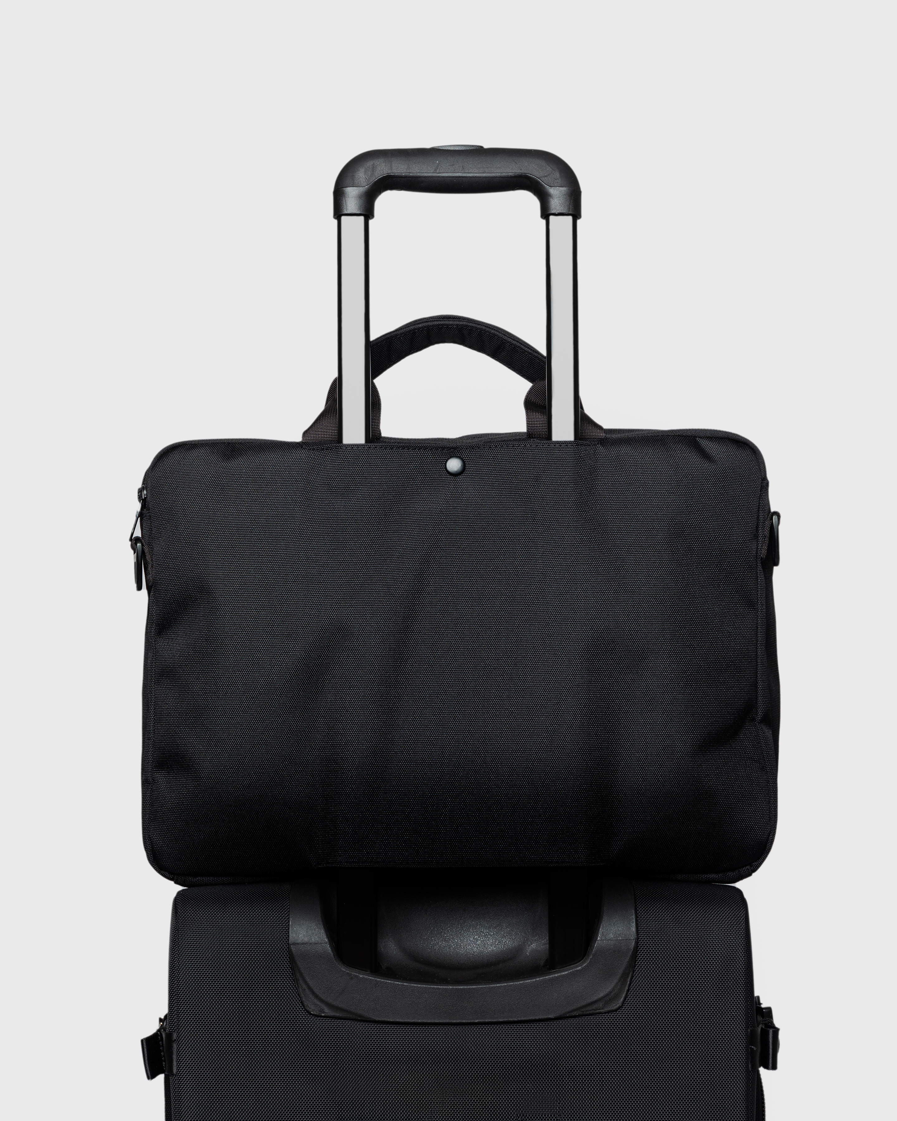 GO Briefcase, black. Back view, attached to a cabin bag with the trolley sleeve.