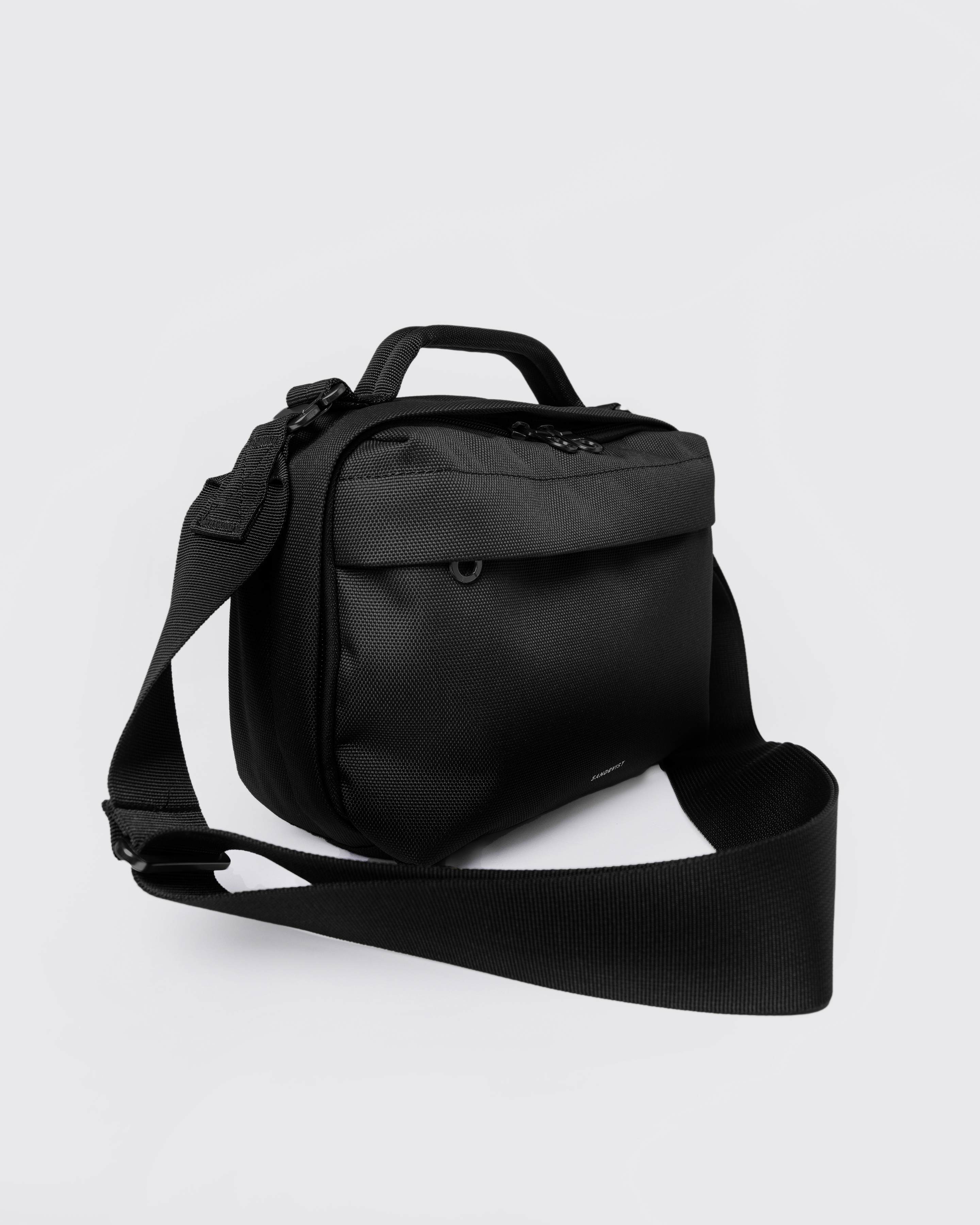 Sandqvist GO Shoulder Bag, black. Front view, handle, shoulder strap and front zipper pocket.