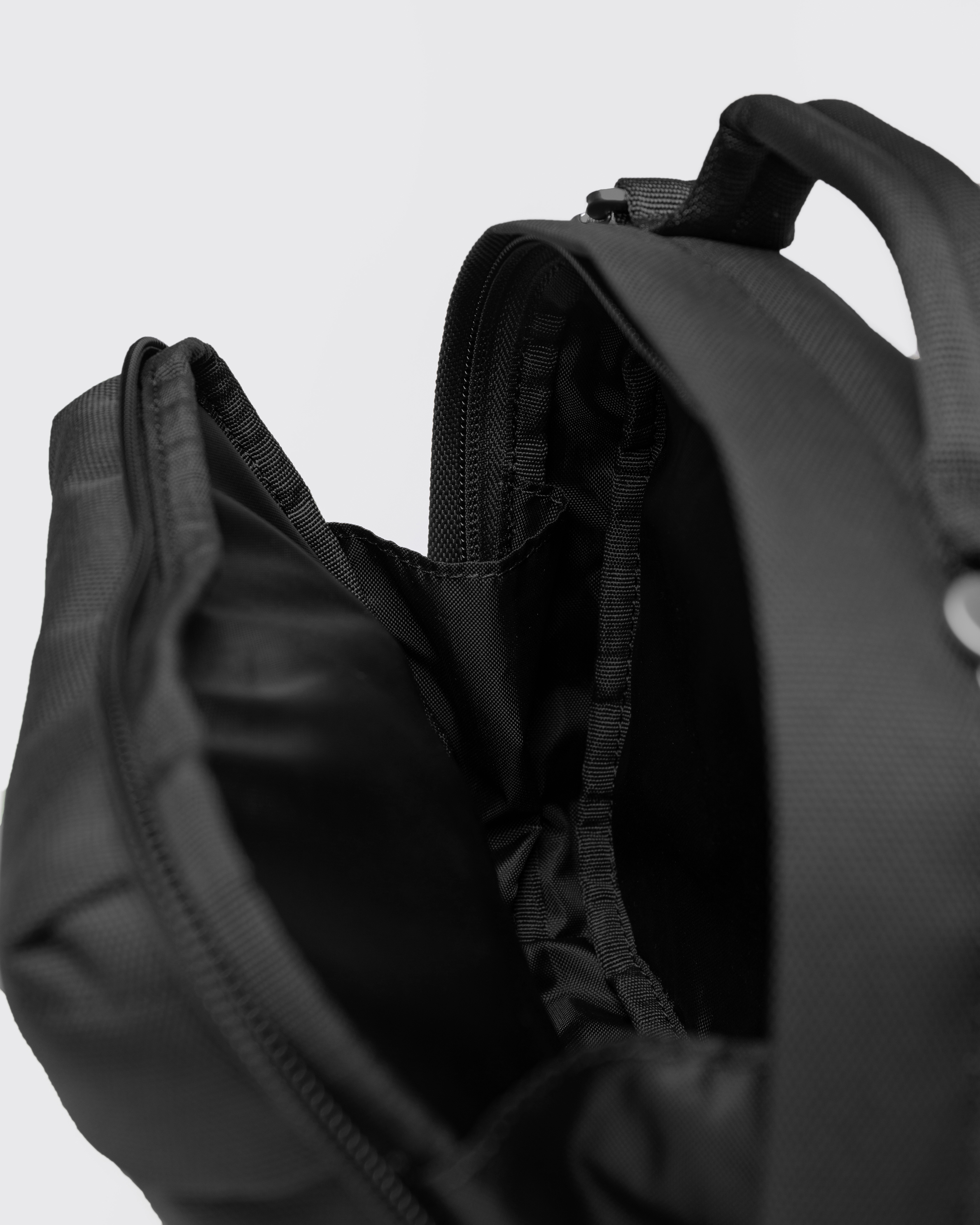 Sandqvist GO Shoulder Bag, black. Inside view, one of the compartments with a zipper, and handle.