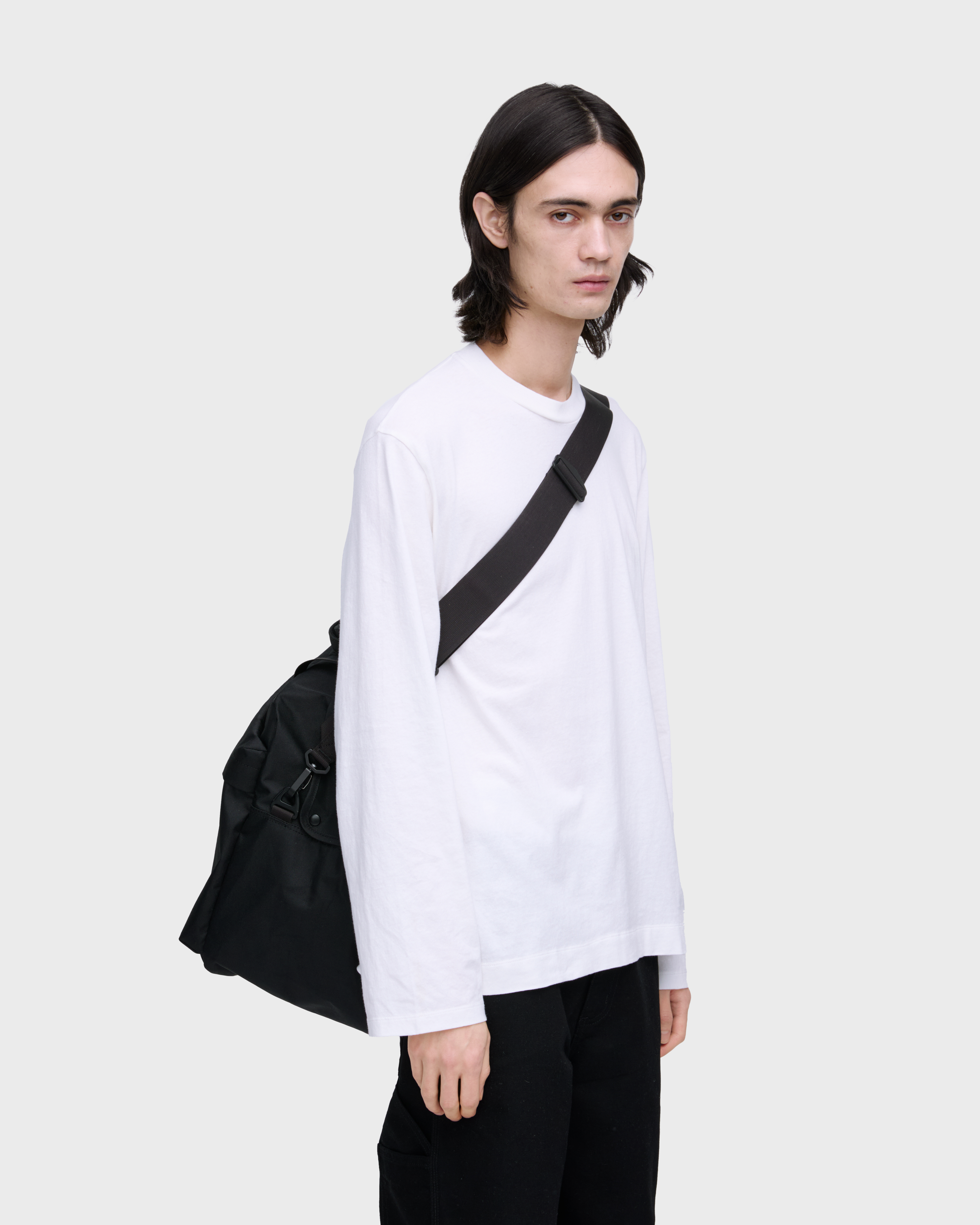 Male model wearing Sandqvist GO Weekender L, black. Front view, wearing the bag on one shoulder crossbody.