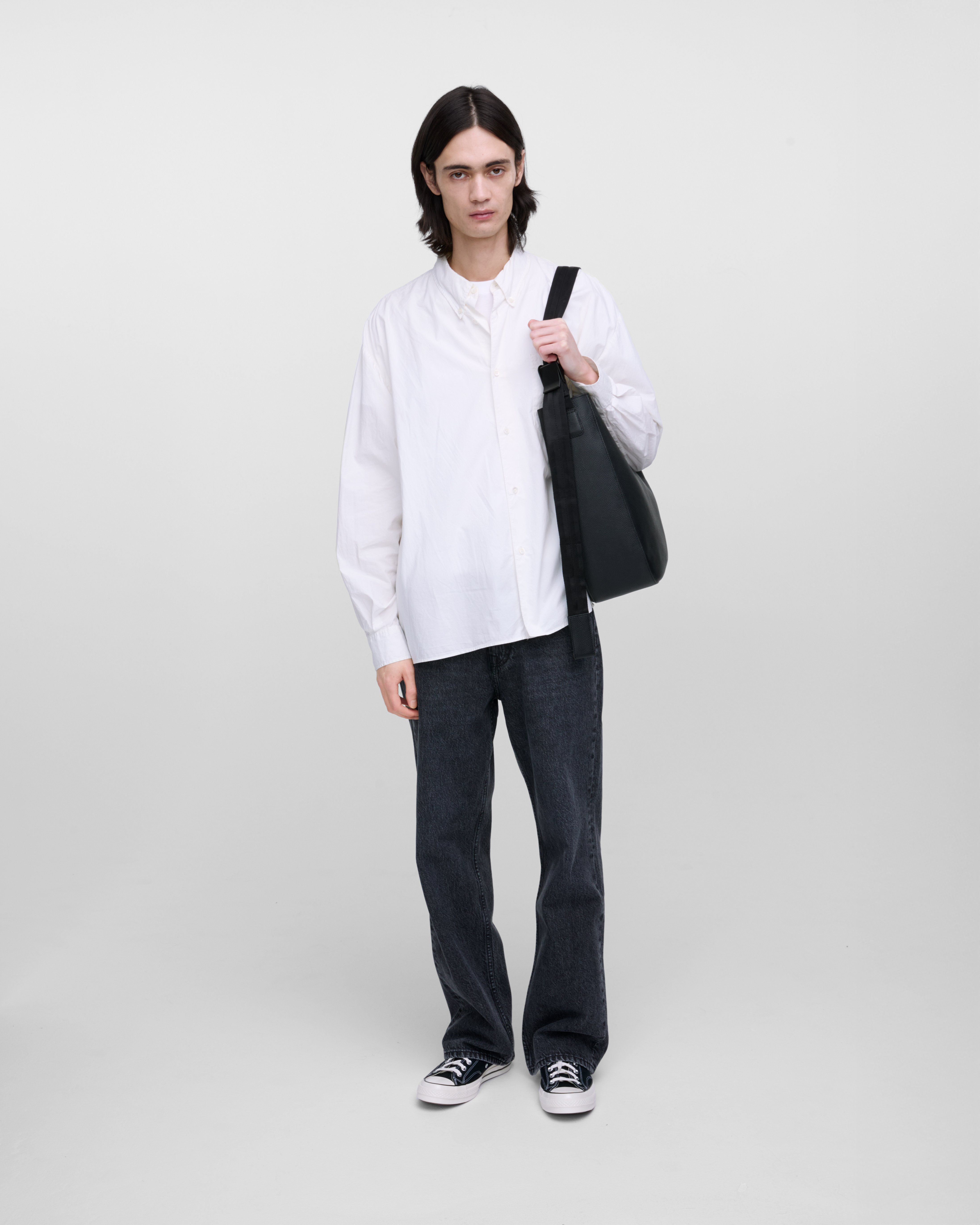 Male model wearing Sandqvist Agile Hobo Tote Bag, black. Front view, wearing the bag on one shoulder.