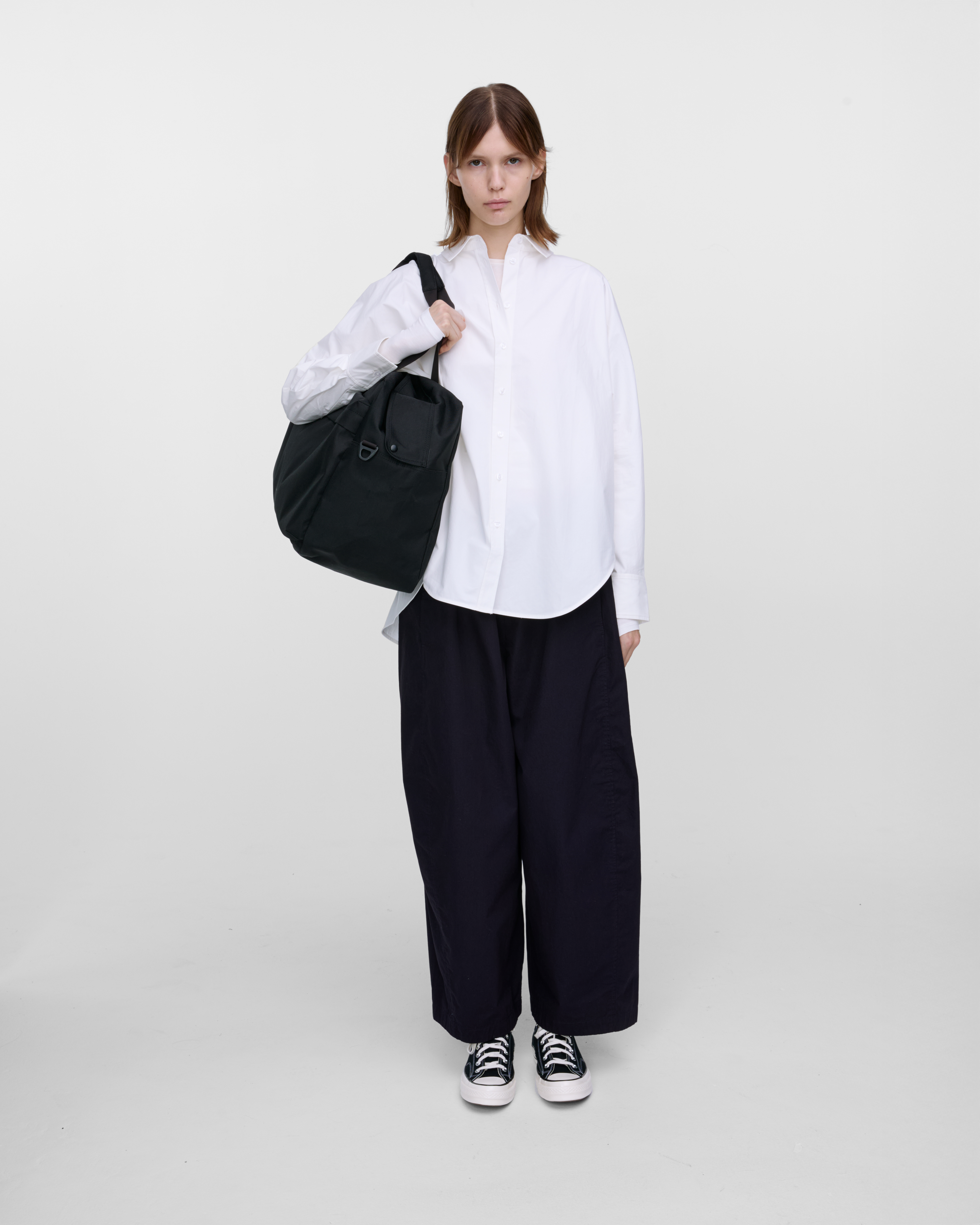 Female model wearing Sandqvist GO Weekender L, black. Front view, wearing the bag on one shoulder.