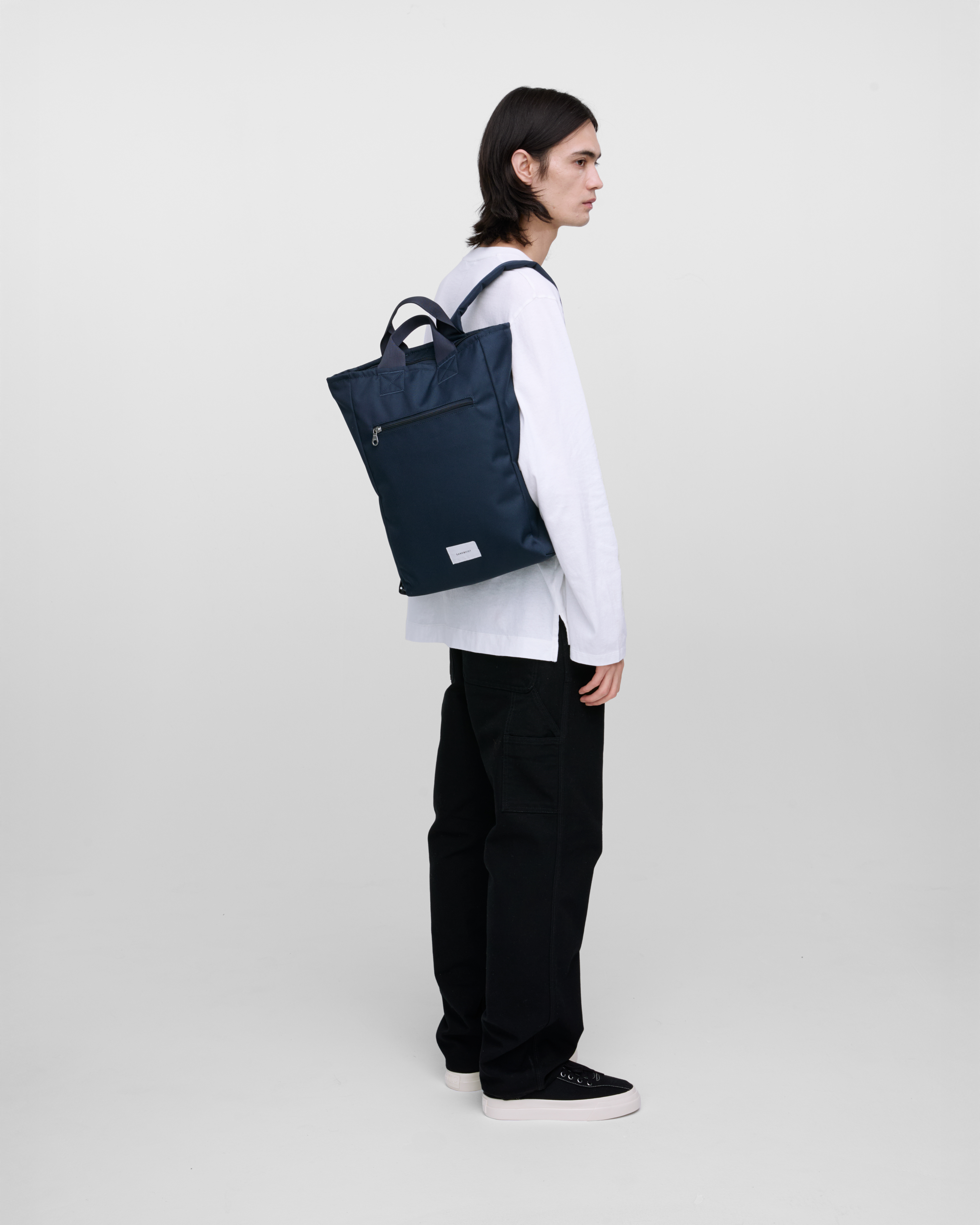 Male model wearing Sandqvist Ground 2-way Bag, blue. Side view, wearing the bag on one shoulder.