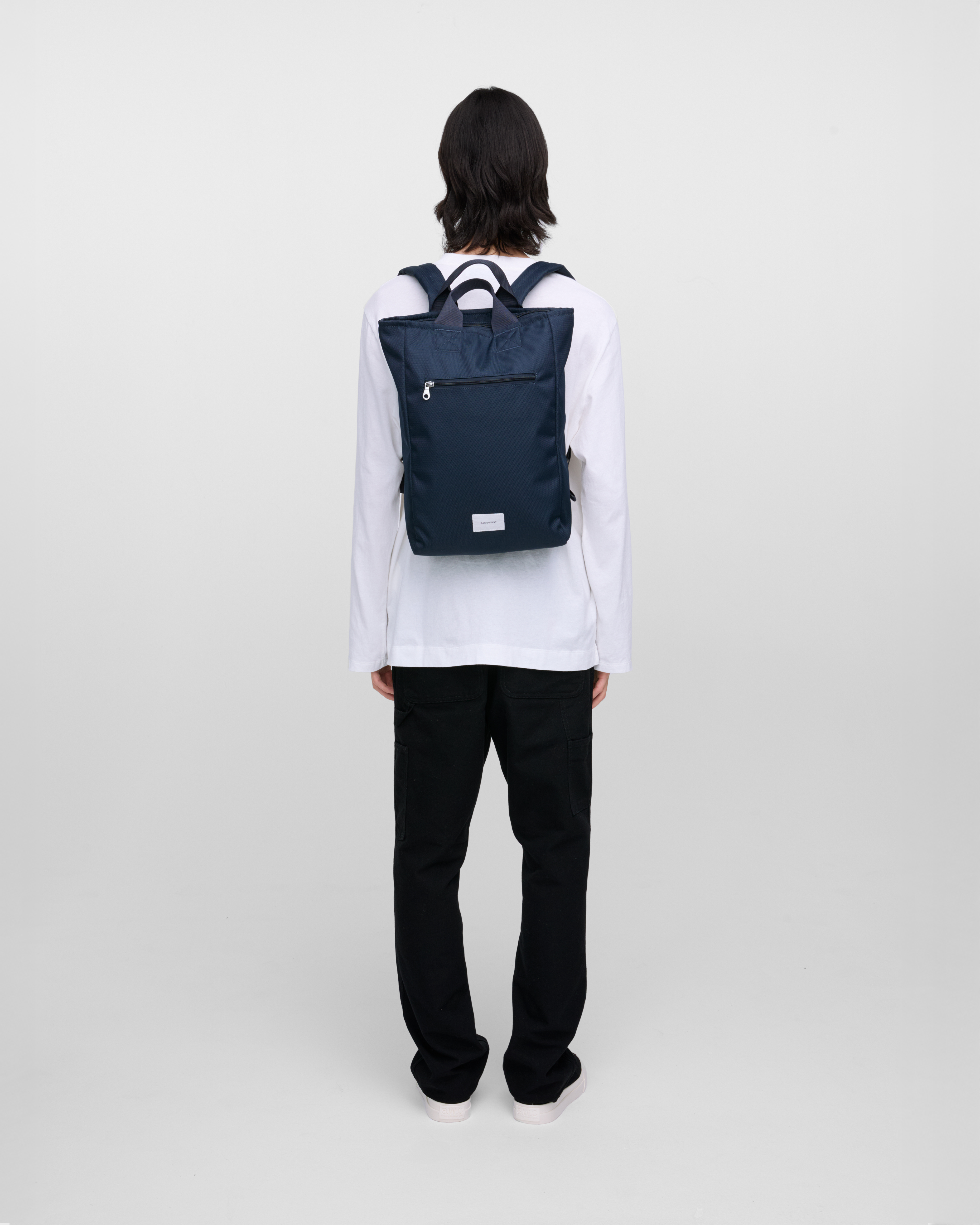 Male model wearing Sandqvist Ground 2-way Bag, blue. Back view, wearing the bag on the back.